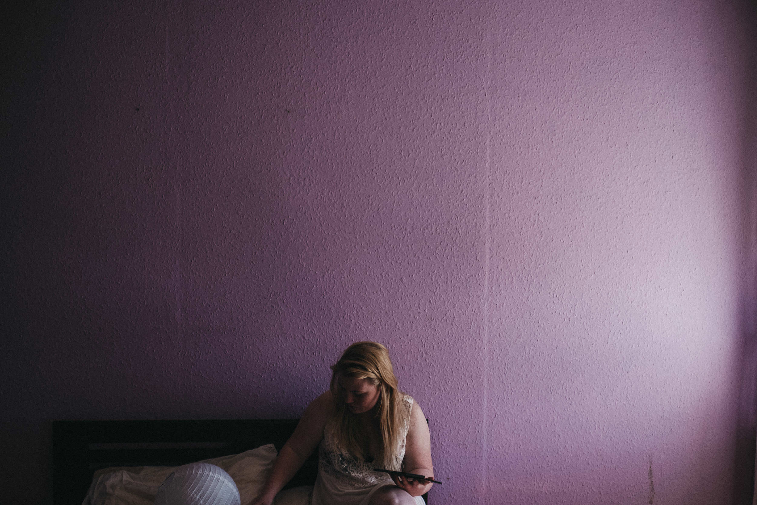 Bride putting on makeup in front of purple wall
