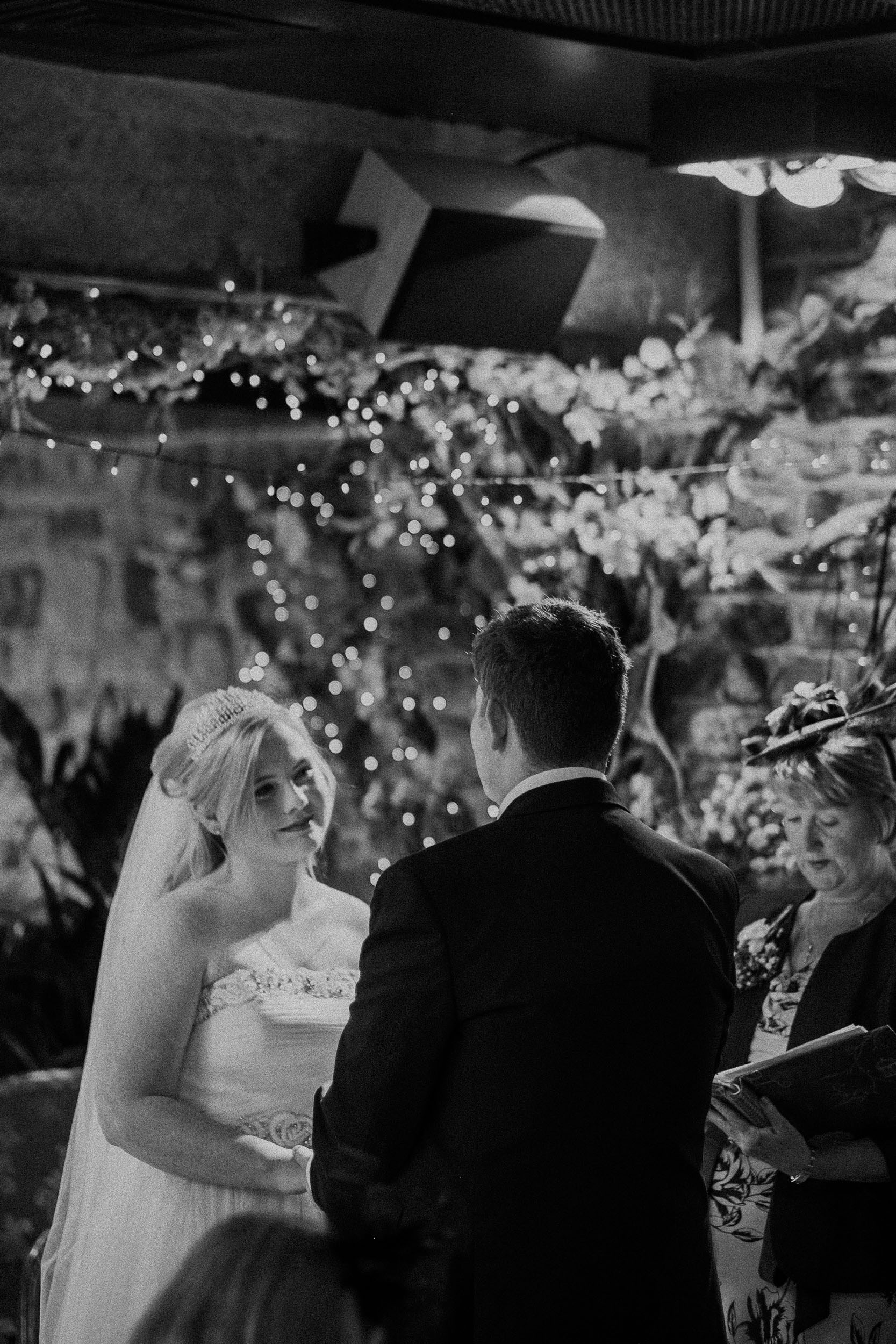 Black and white photo of bride looking longingly at groom during ceremony