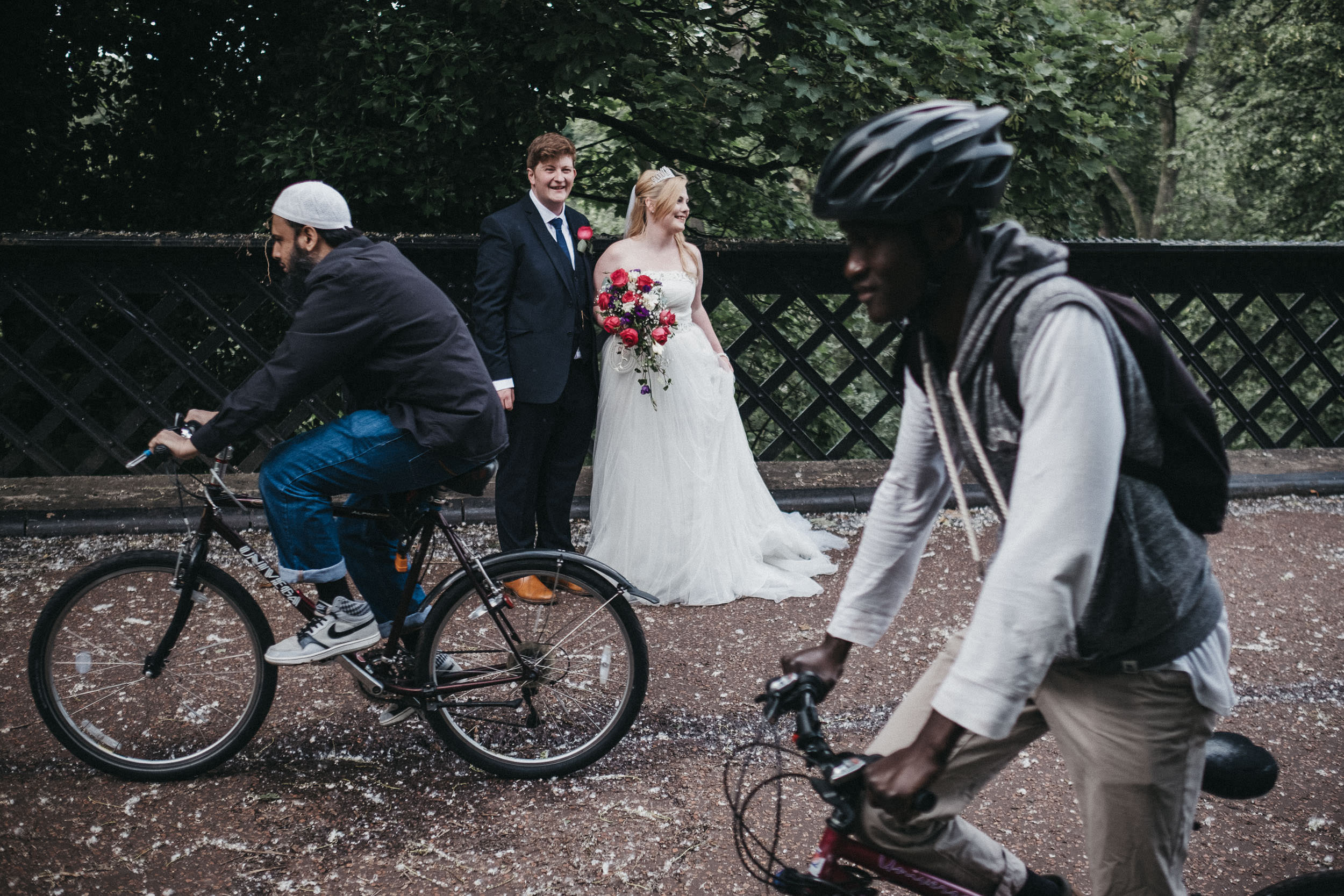 Bride and groom laughing as cyclists ride past