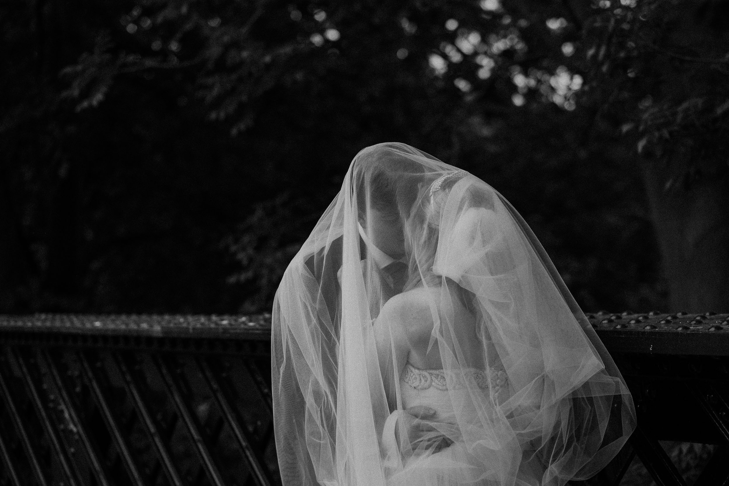 Black and white photo of bride and groom under bride's veil
