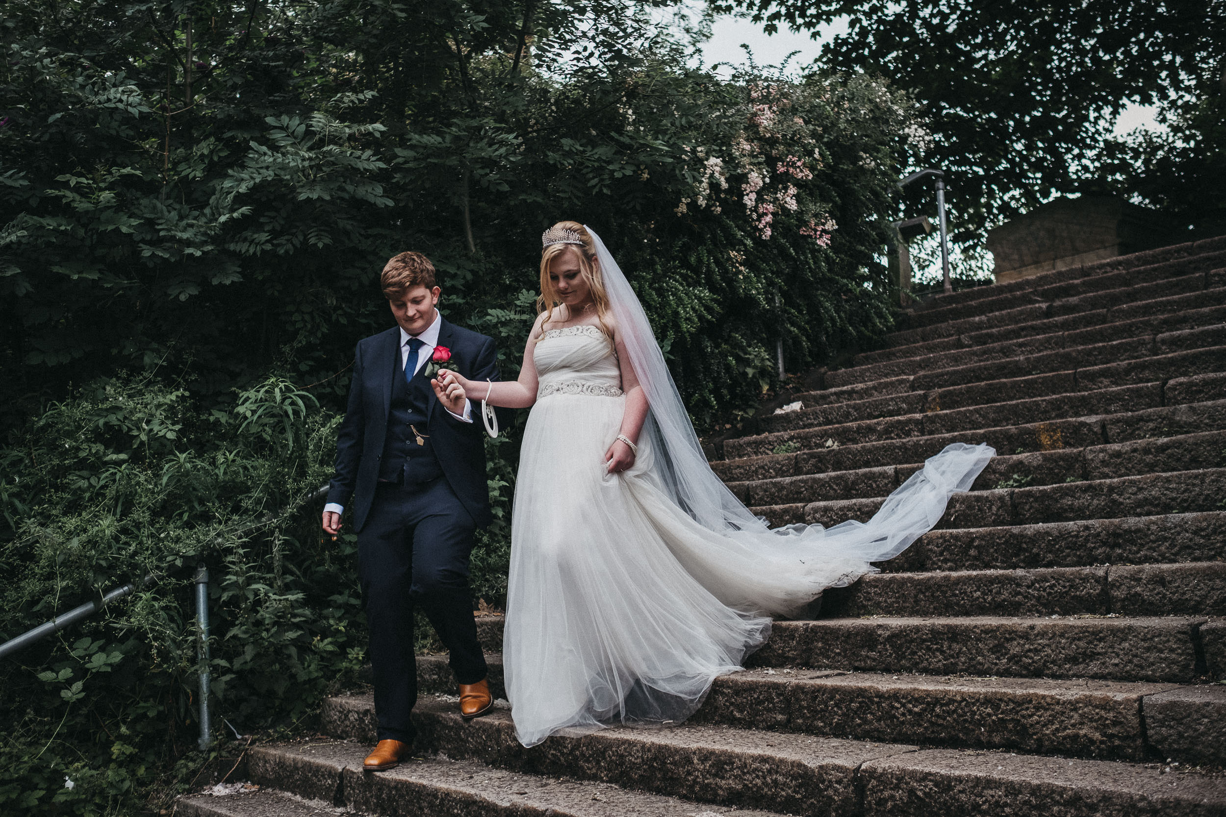 Groom holds bride's hand as they walk down stairs