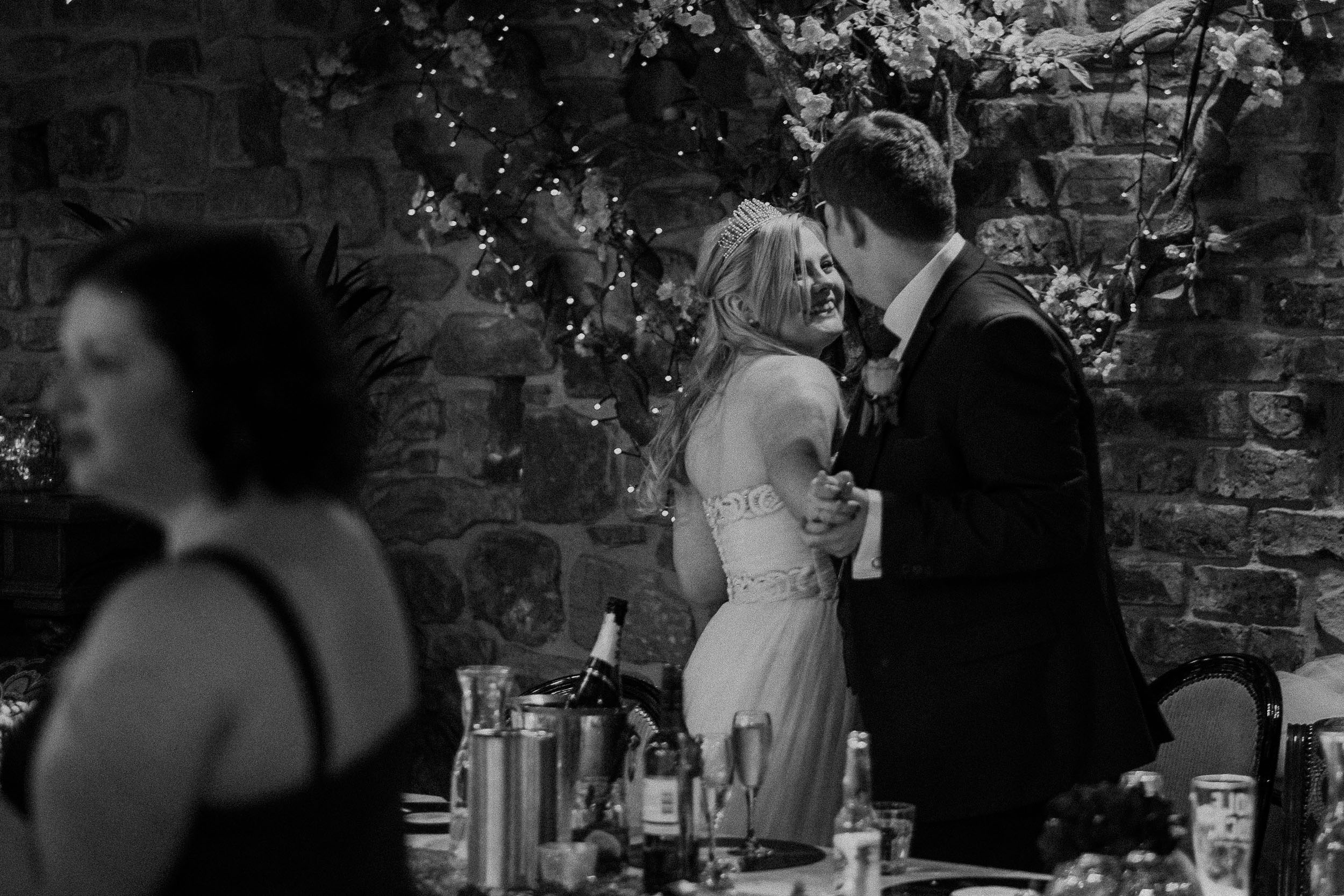 Black and white photo of bride and groom hugging and laughing at As You Like It