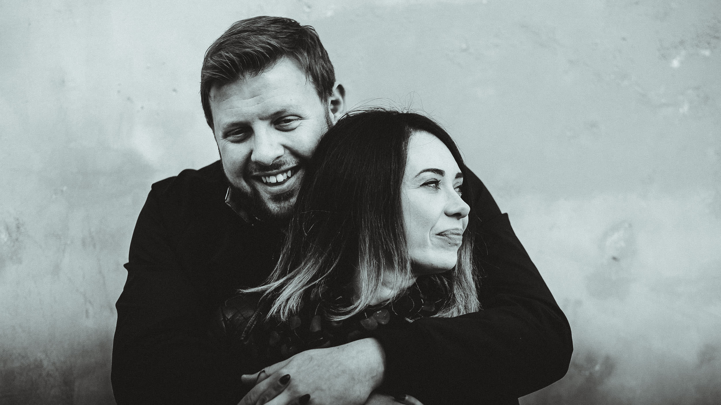 A black and white close up photo of a couple cuddling and laughing