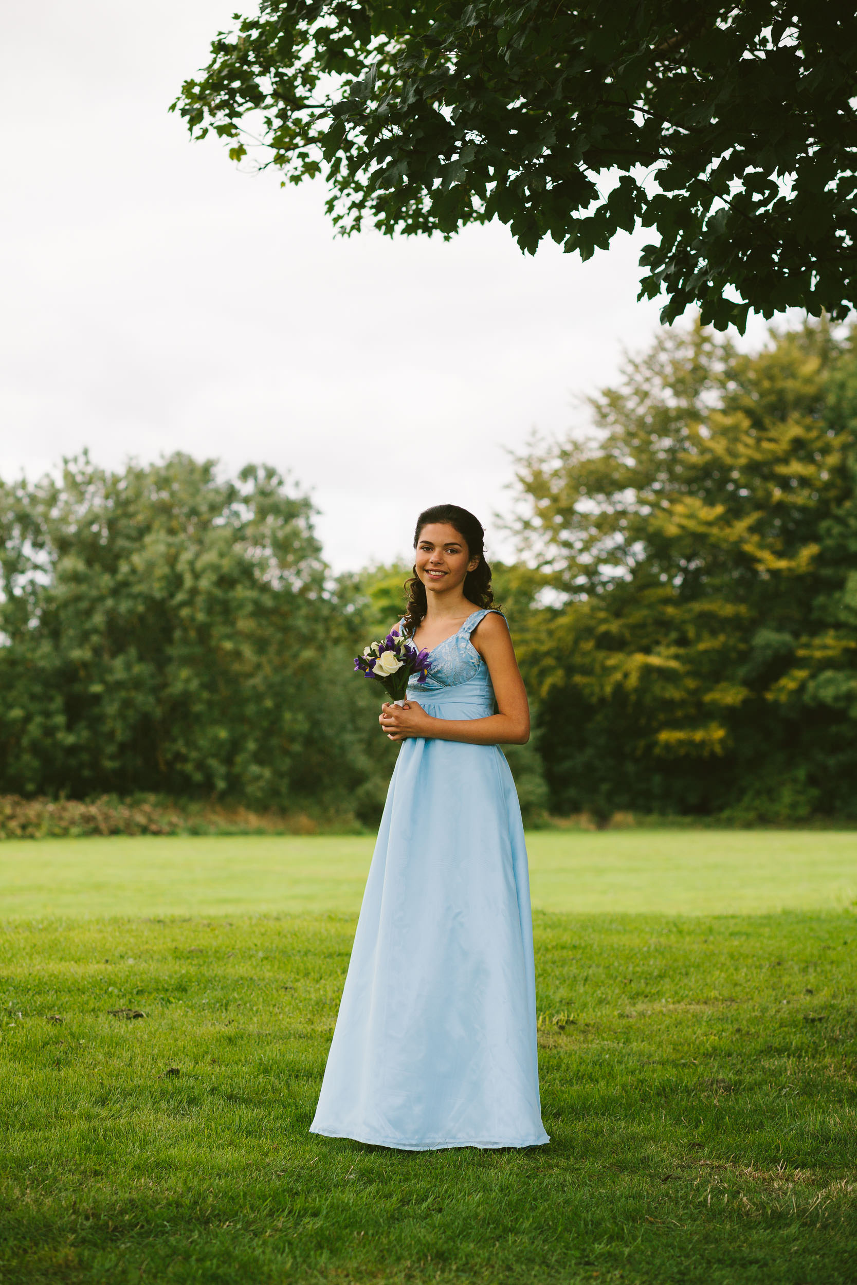 Bridesmaid poses with flowers under tree