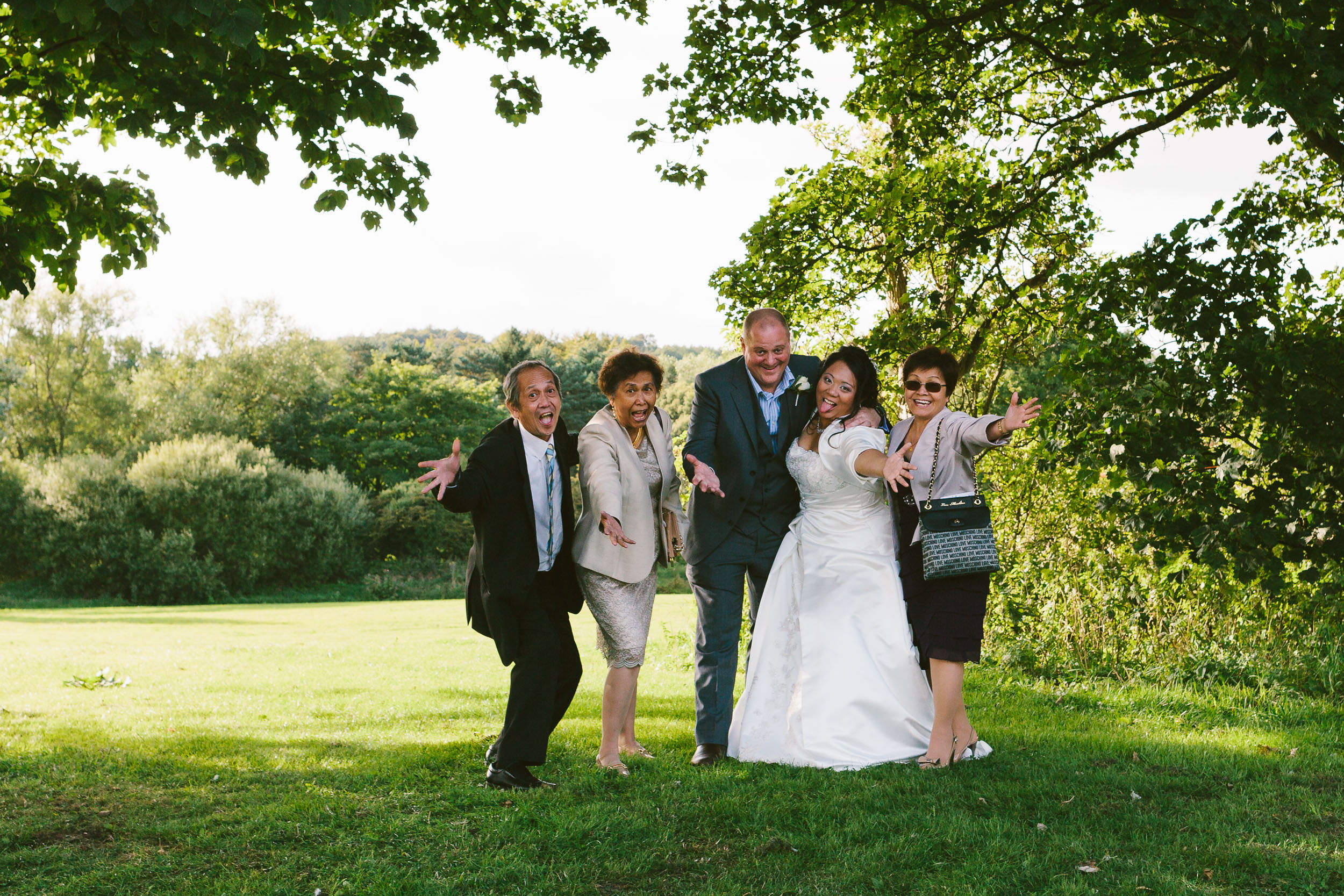 Bride, groom and guests pull funny face during wedding photos