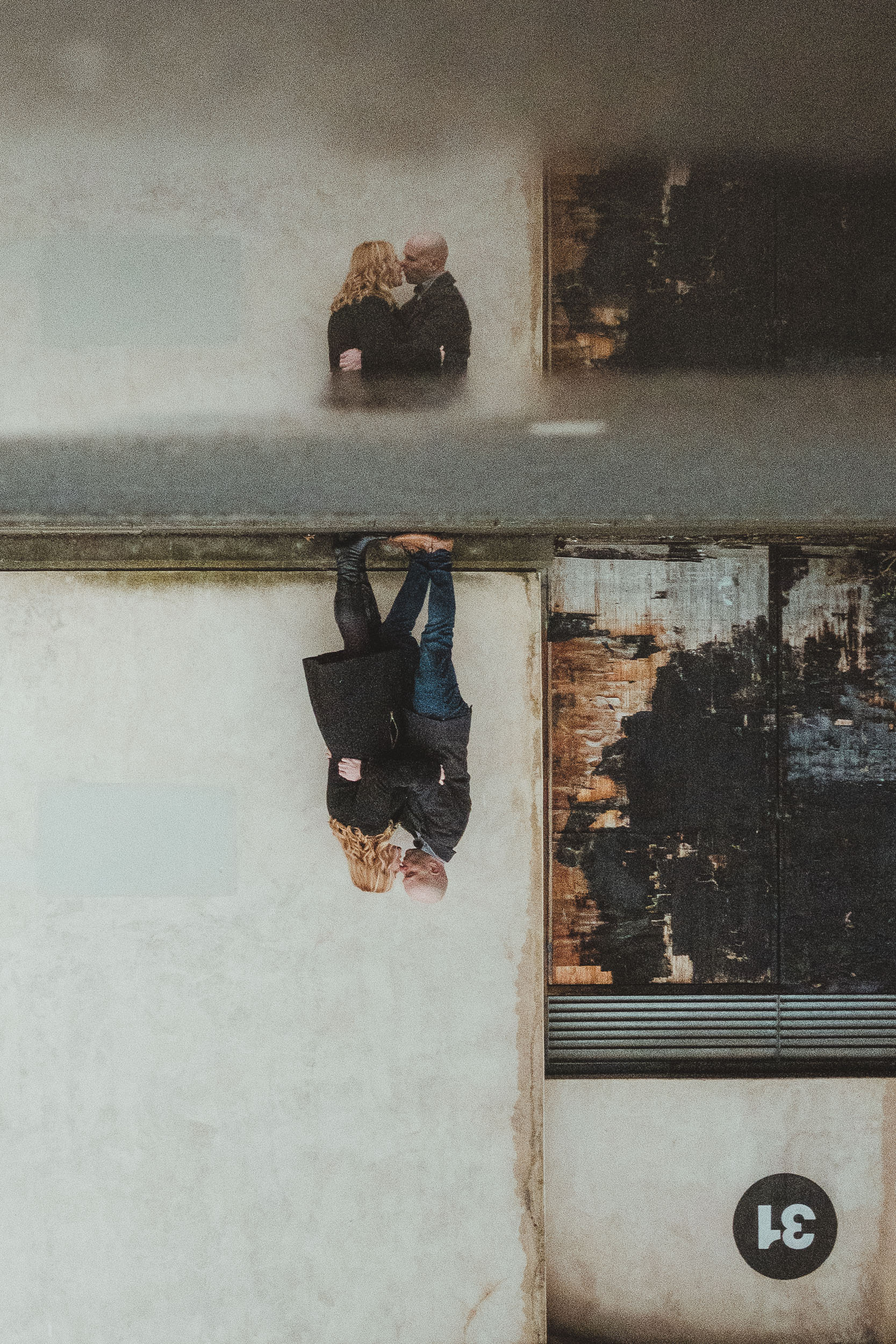 A couple kiss while reflected in a puddle on Newcastle Quayside