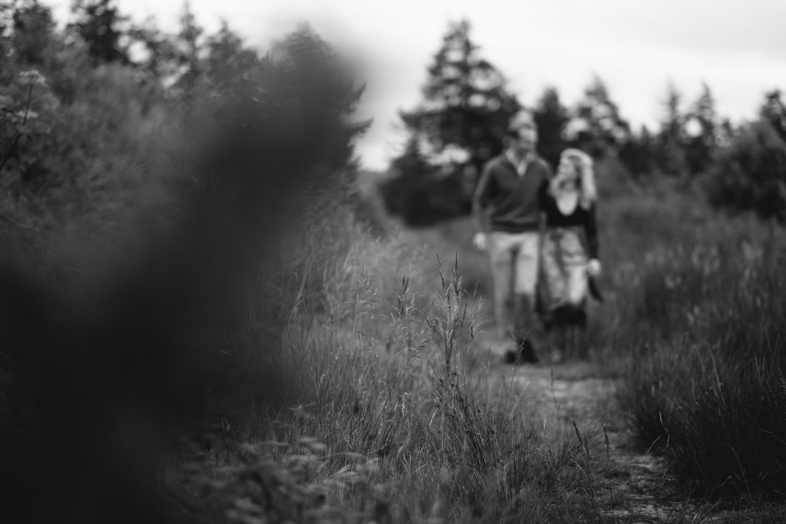 A black and white photo of a couple walking arm in arm down a path