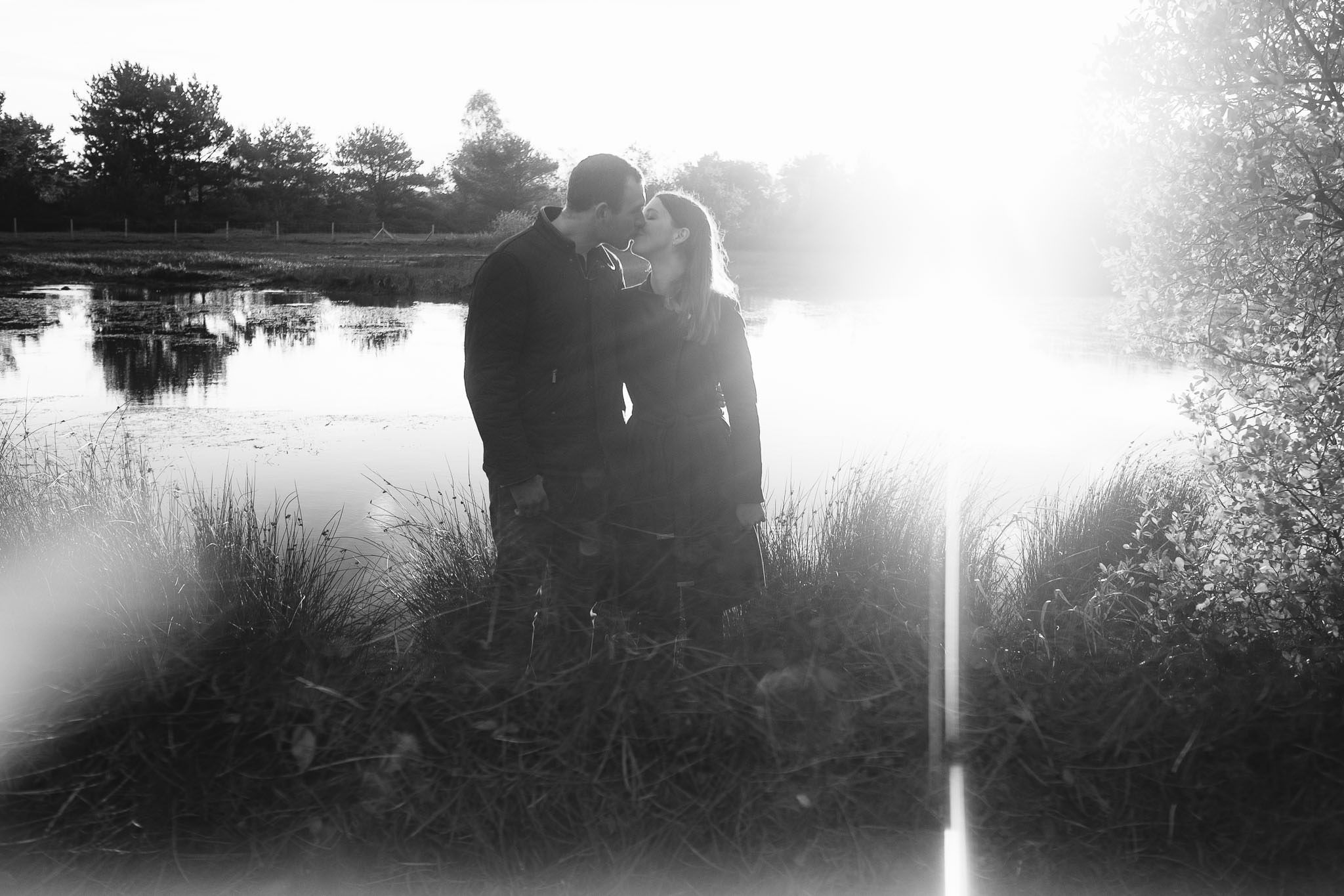 A black and white photo of a couple kissing in front of a lake, reflected in a prism