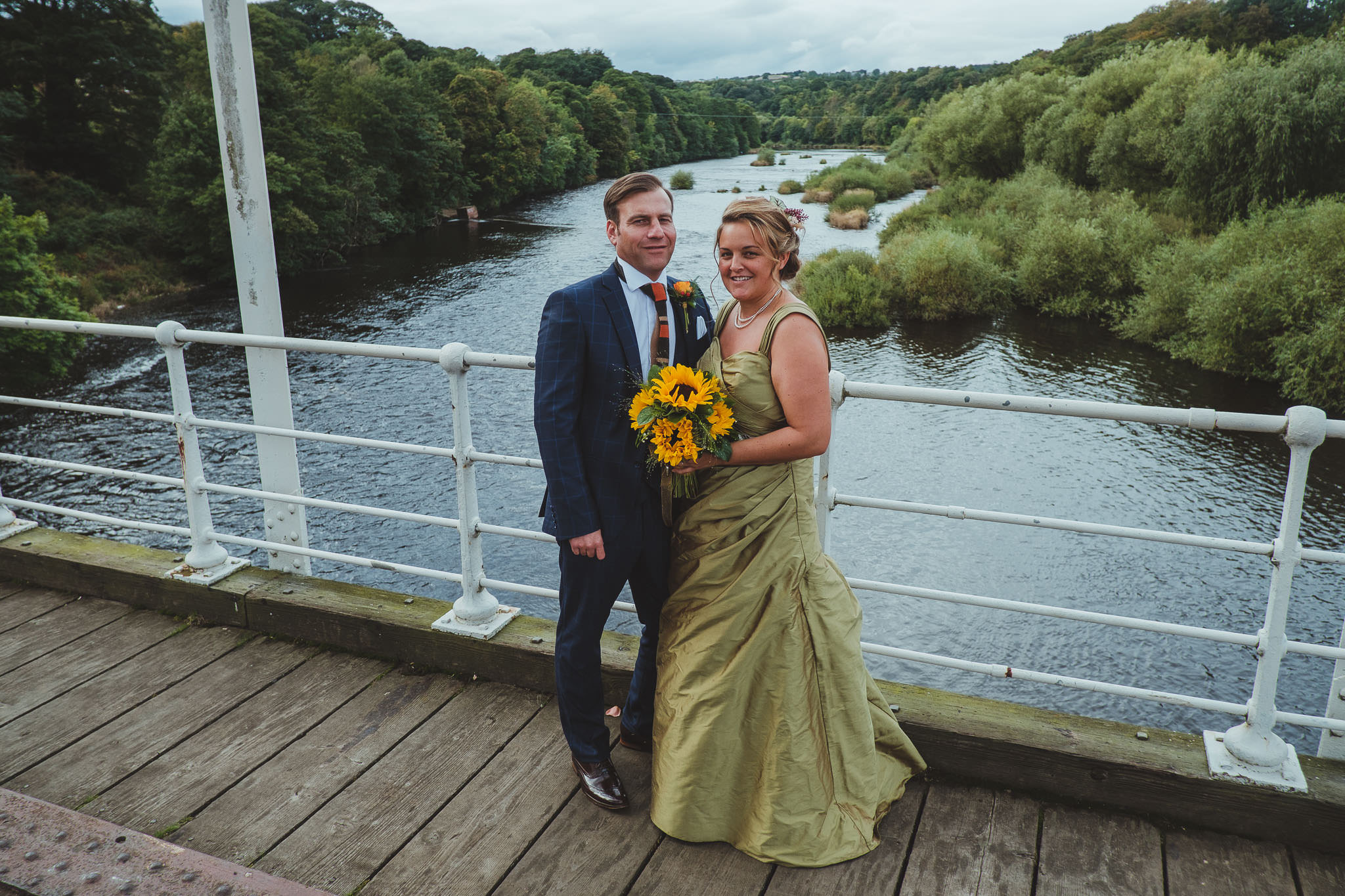 Bride and groom pose on a bridge over the River Tyne