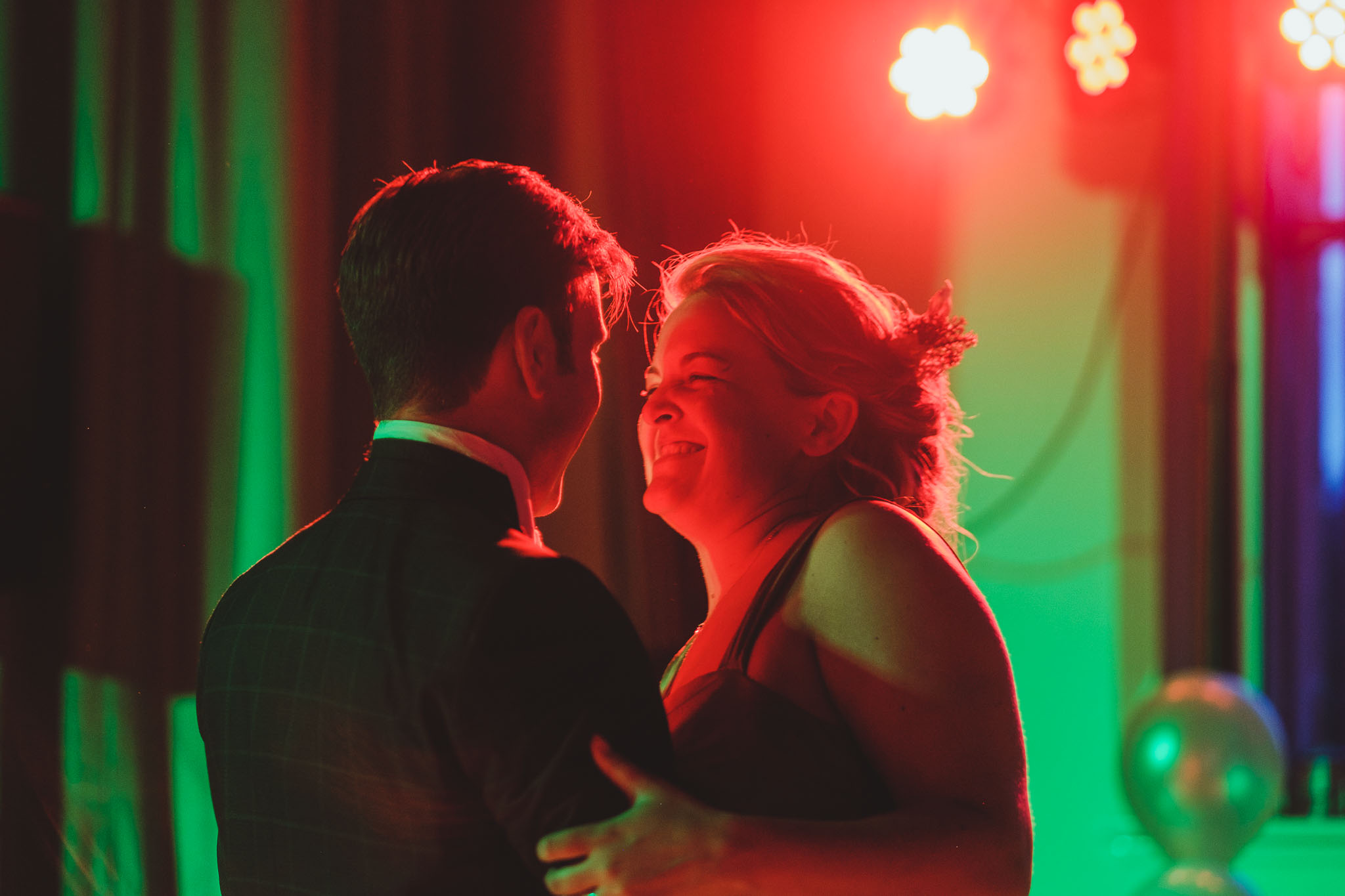 Close up of bride and groom first dance in green and red light