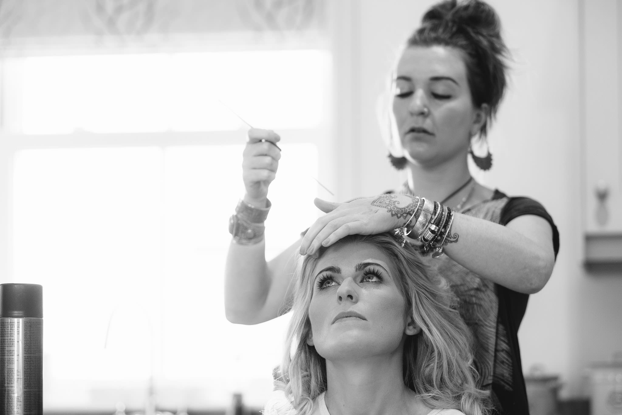 A black and white photo of the bride having her hair dressed