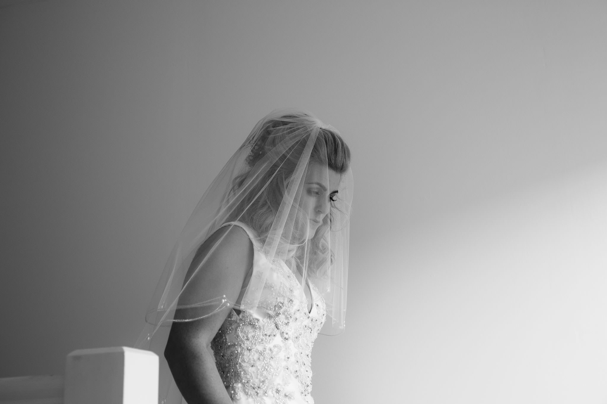 A black and white photo of the bride in her veil before the ceremony