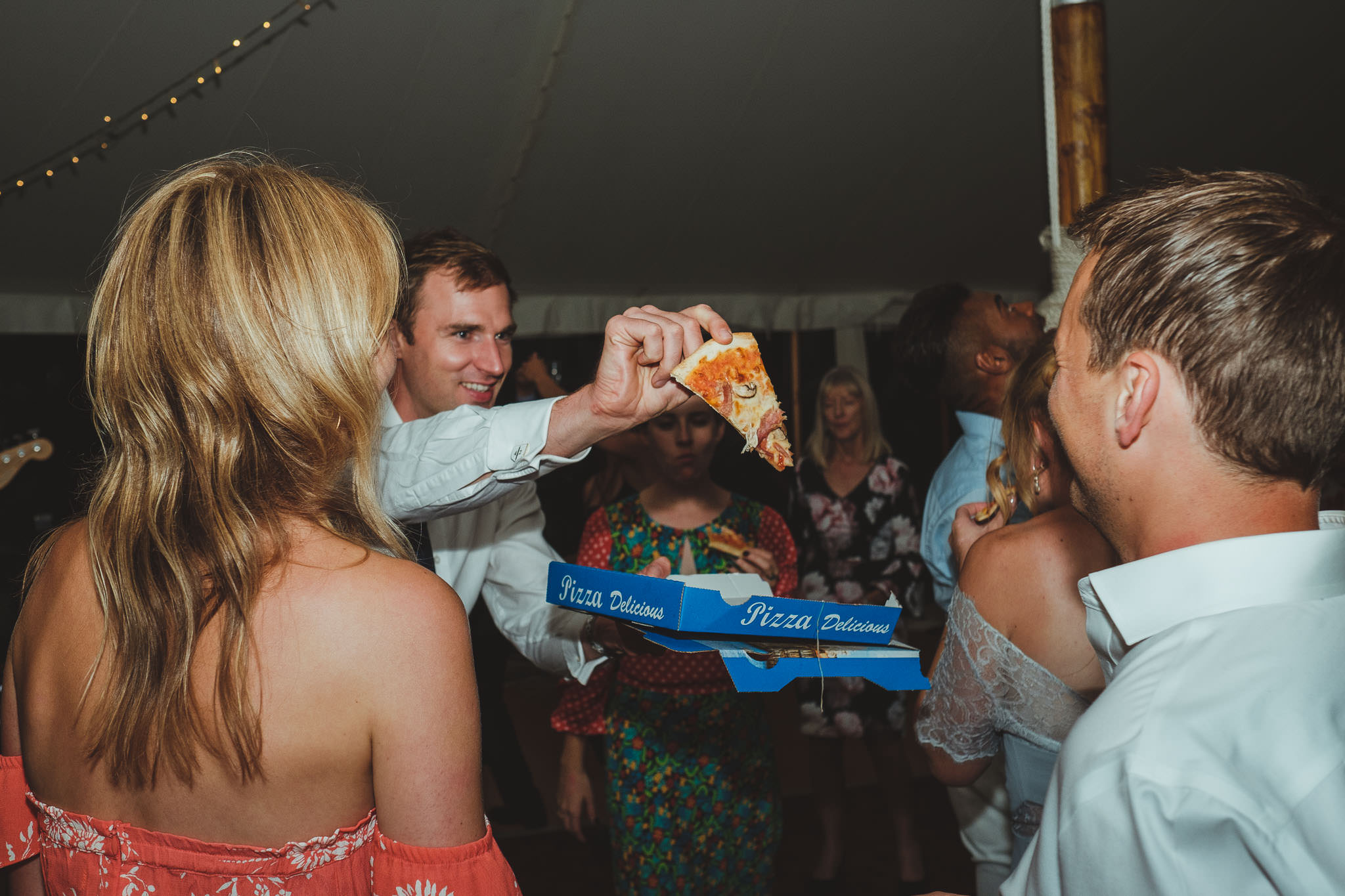 A wedding guest waves a slice of pizza on the dance floor