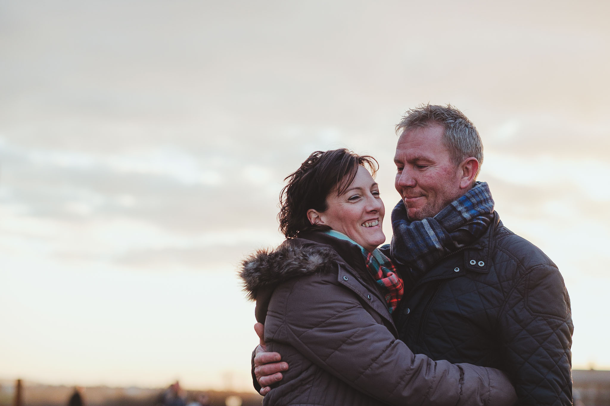 Couple cuddle and smile while on pre wedding session on Tyneside coast