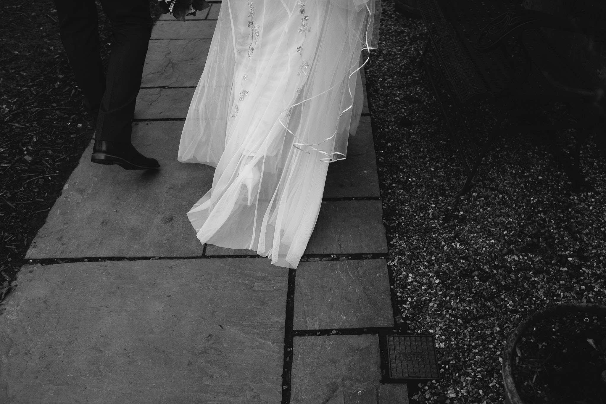 Black and white close up photo of the bride's dress as she arrives at the wedding venue