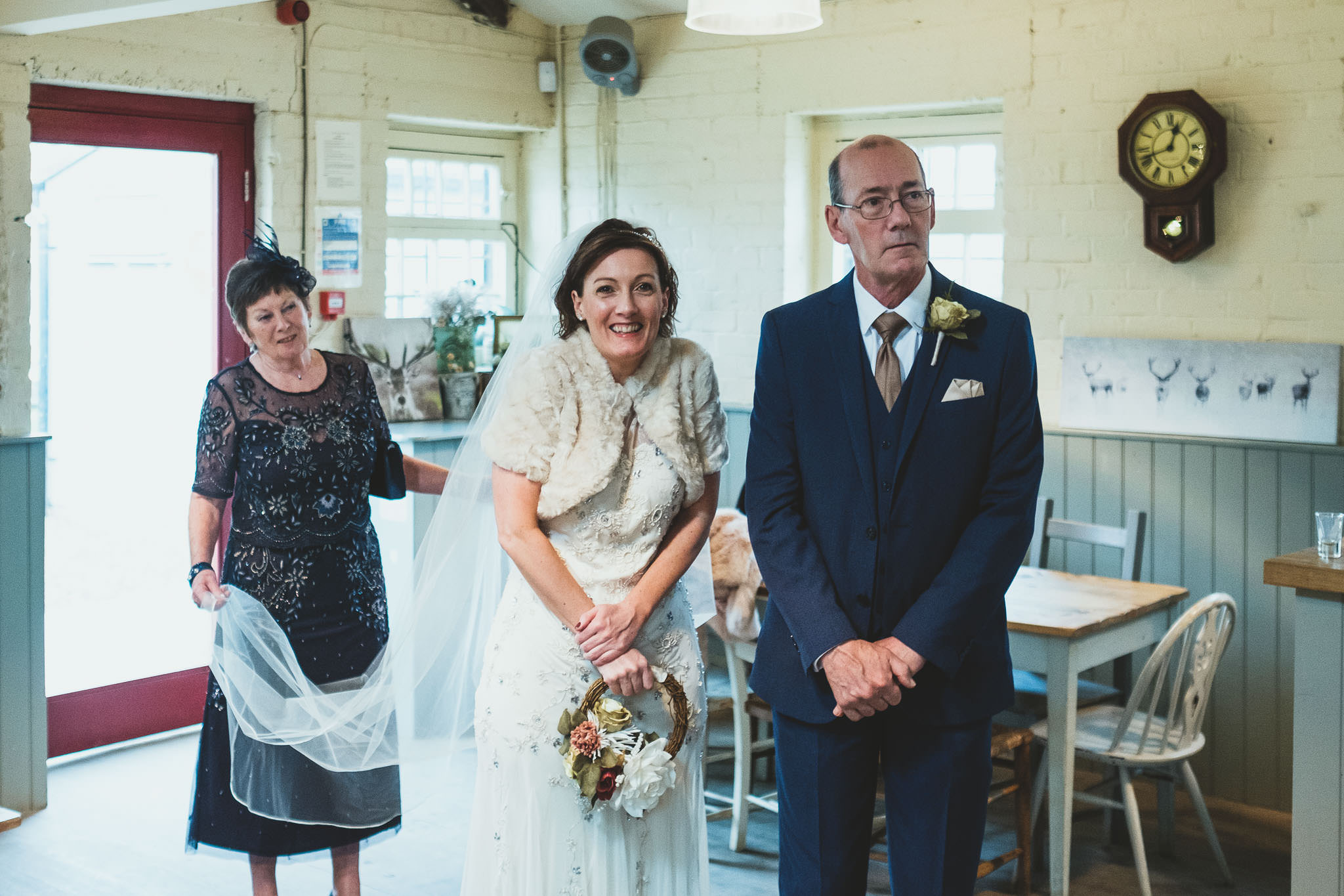 Bride smiles while her mother holds her wedding train