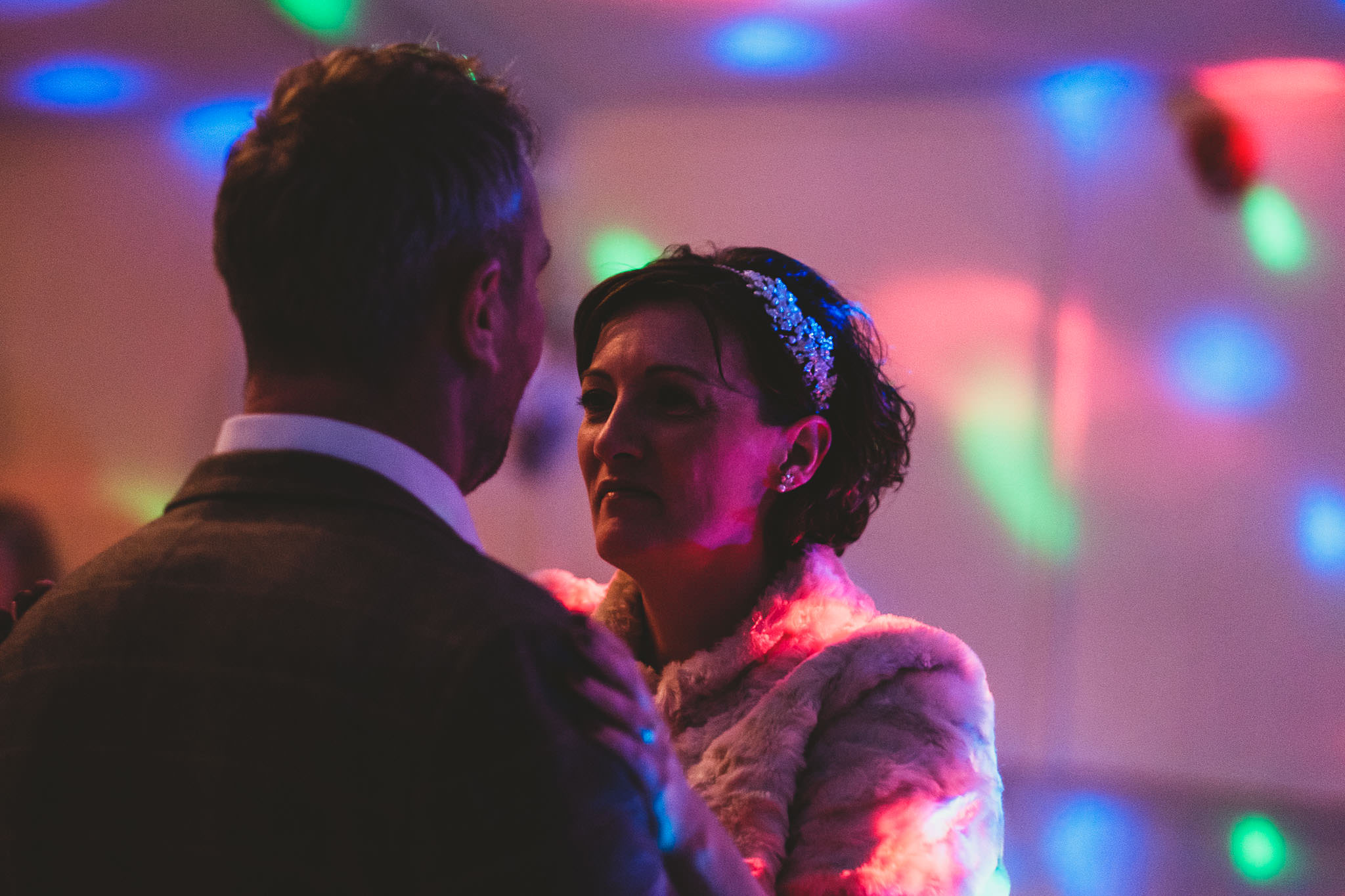 Bride and groom first dance lit by disco lights