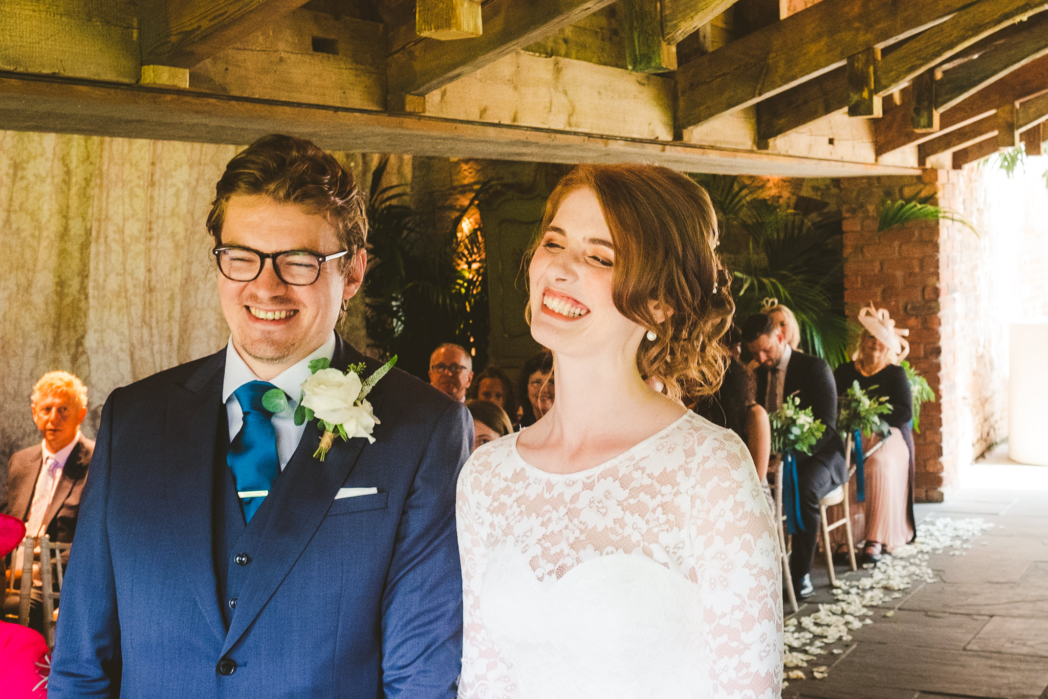 Bride and groom smile during their wedding ceremony in the Garden Suite at Newton Hall