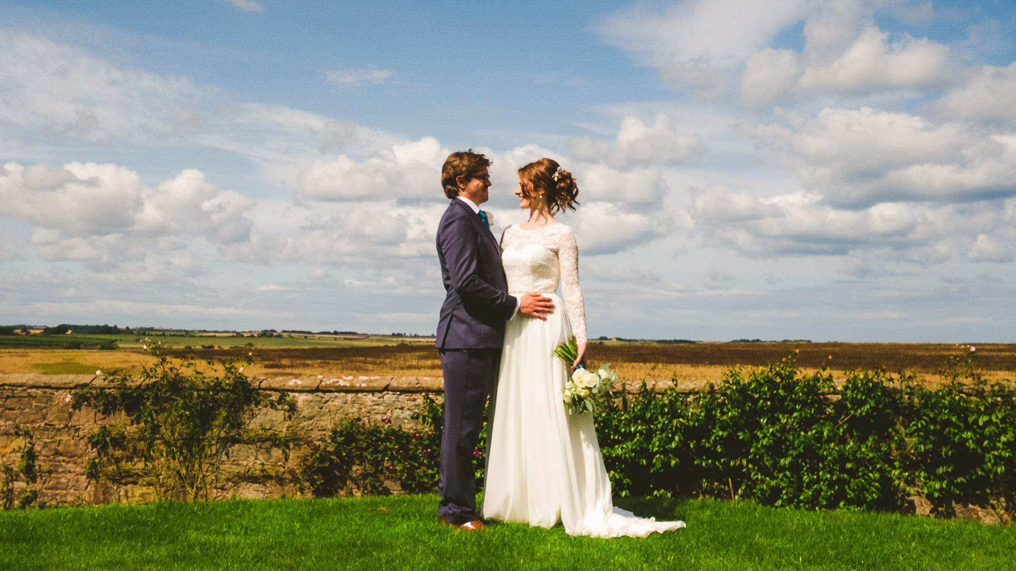 Bride and groom hold each other with the Northumberland countryside in the background