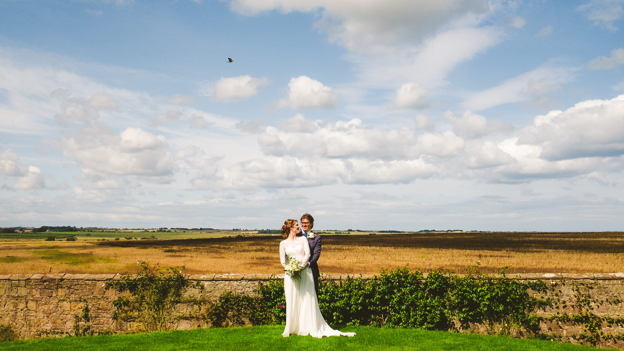 Wide view of the Northumberland countryside with bride and groom in the centre of the frame