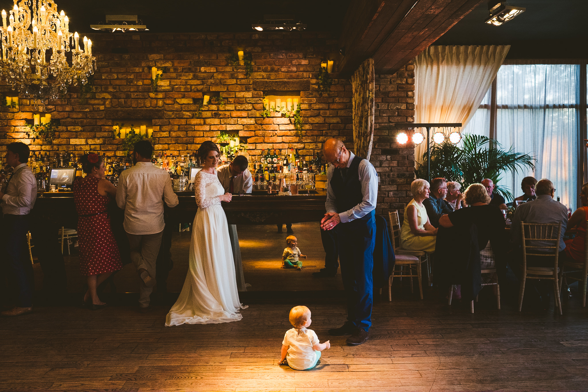 Bride watches baby crawling on floor at bar in Newton Hall