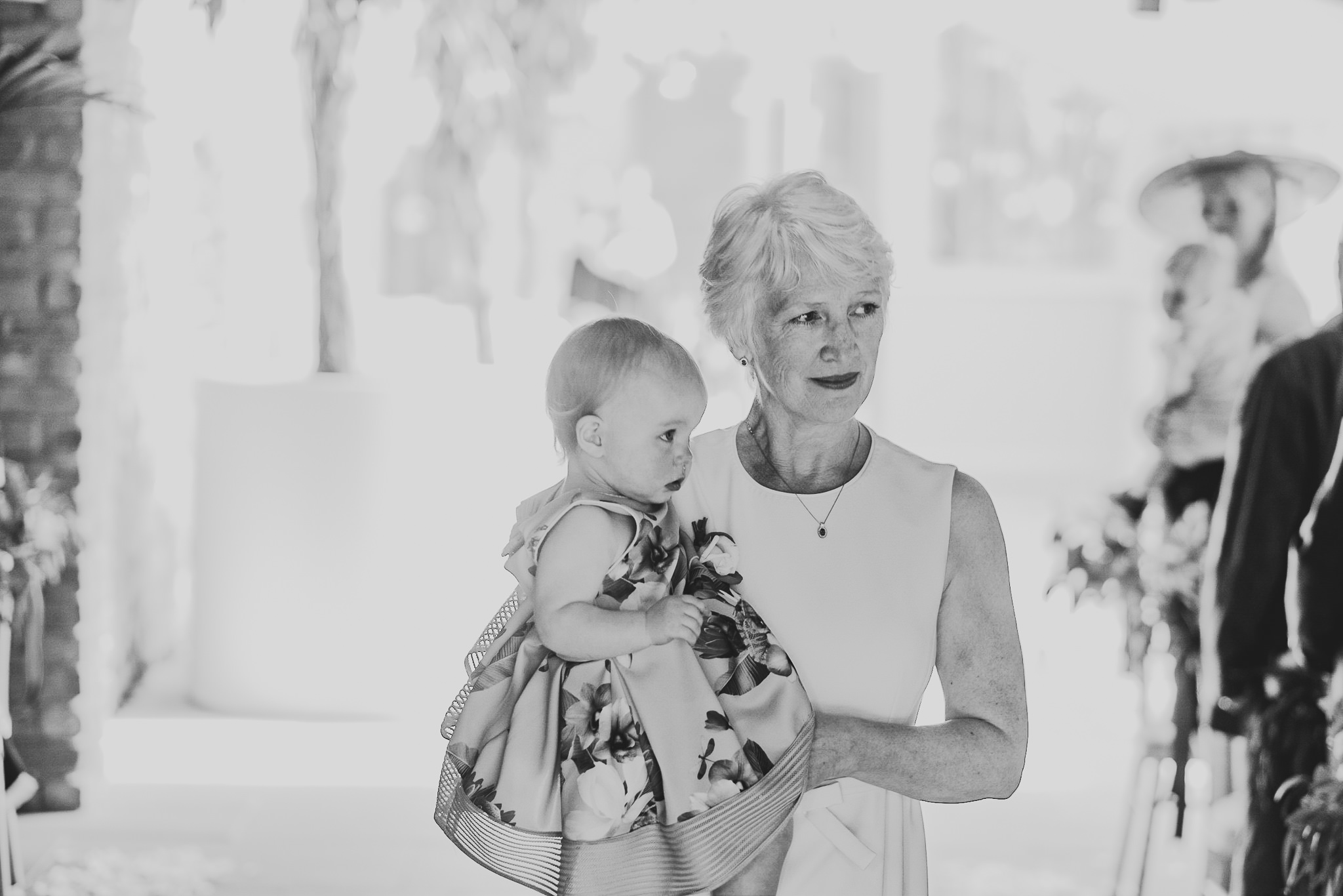 A black and white photo of the mother of the bride carrying in the bride's daughter to the ceremony