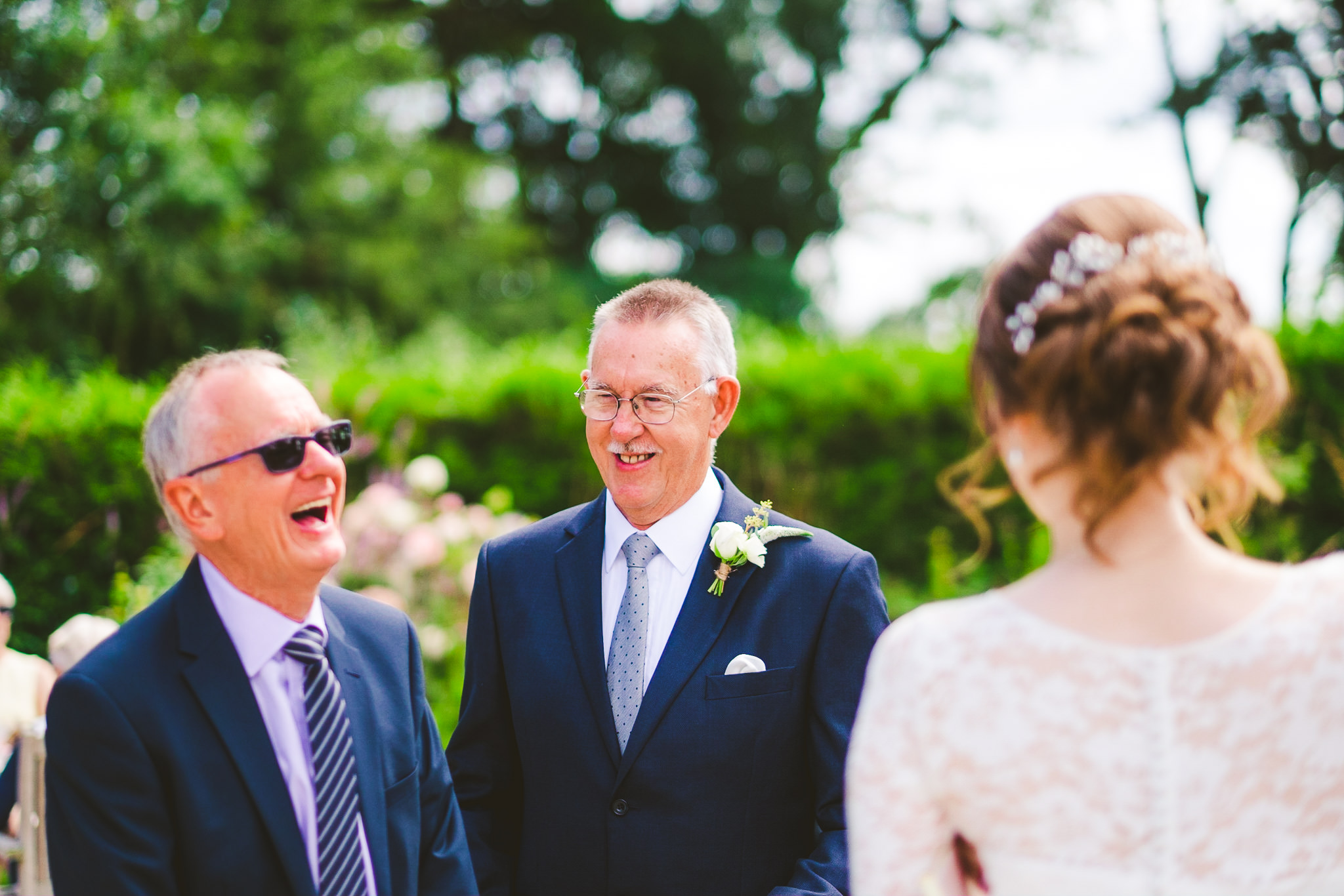 Wedding guests laugh while relaxing outside