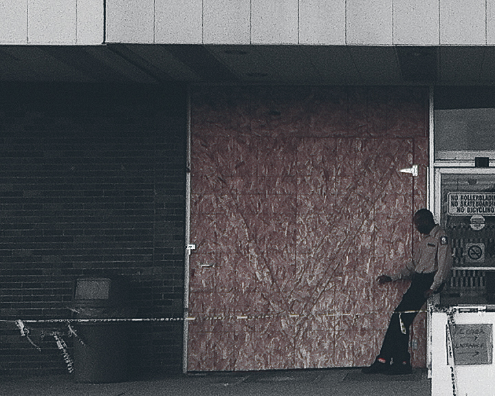 A security guard smokes a cigarette while guarding vacant Fort Richmond Plaza (©Deborah Clague)