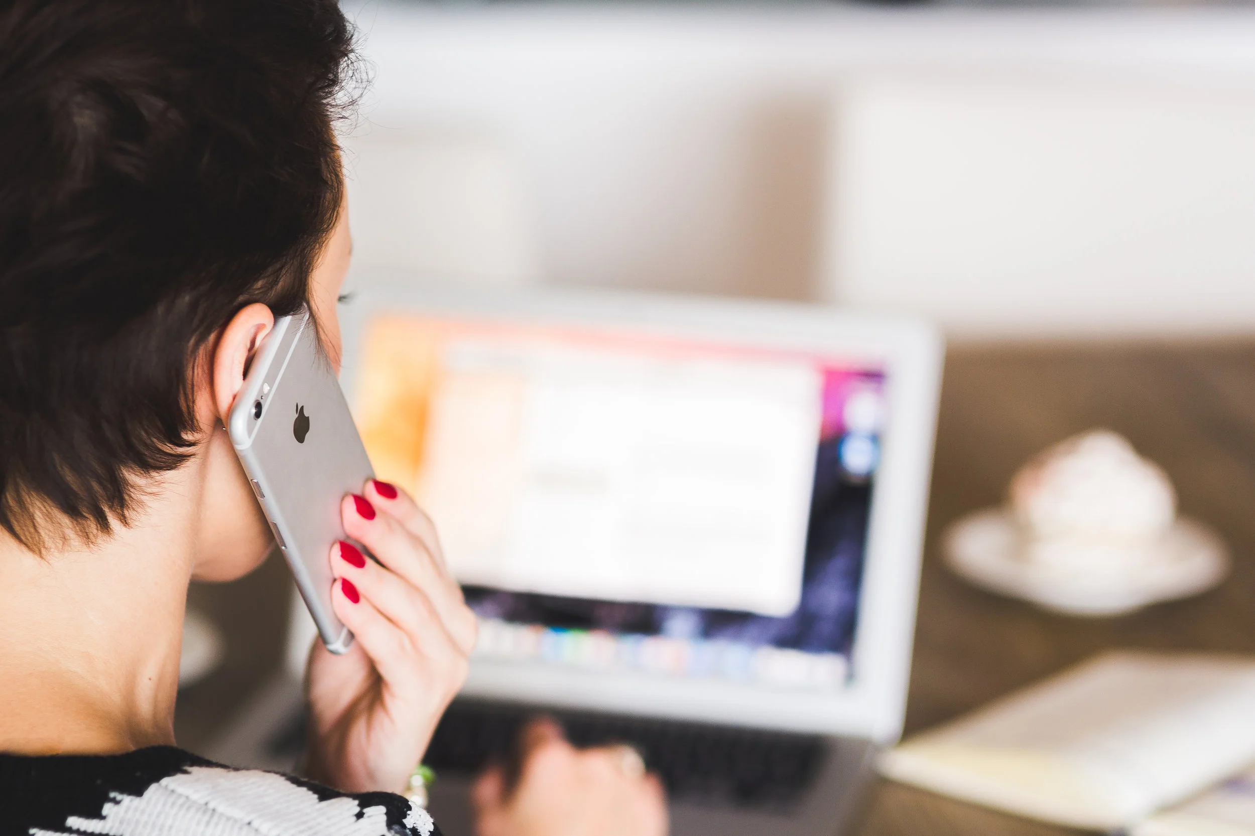 woman talking on phone and using her laptop