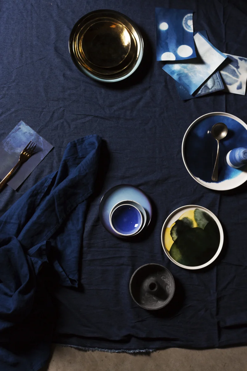 Blauwe tafelloper van H&M Home , Koperen vork van Xenos, Gouden bordjes van &Klevering , Planeetbord 'Diesel' via &Klevering , Bord 'Marrimekko' via &Klevering , Kopjes op de kop 'Alissa en Nienke' via Restored , Lepel eigen, Blauw bordje 'Diesel' via &Klevering , Kleine schaaltjes van Elke van den Berg , Geel groen bord 'Marrimekko' via &Klevering , Kaarzenstandaard van H&M Home , Denim stof van Stoffenkraam