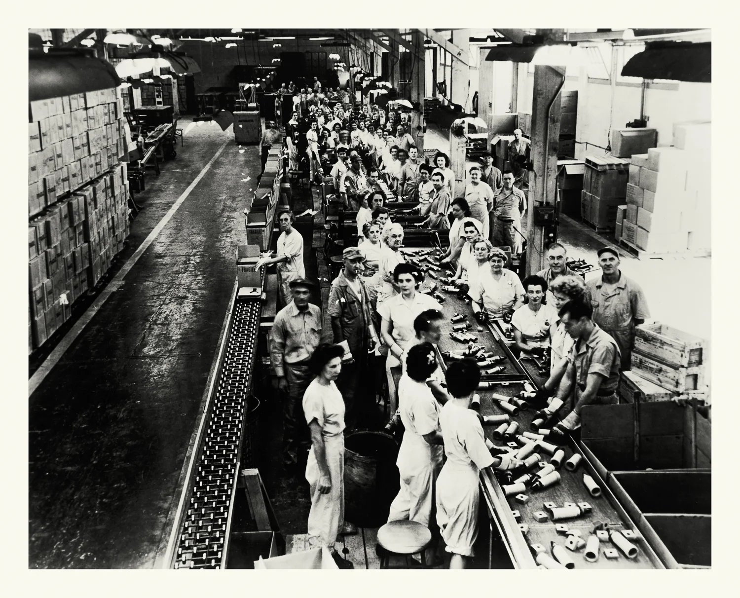  Photograph No. PD 142. “Photograph depicting a line of workers assembling Variable Timing fuses for rockets. These fuses used reflected radio waves to detect proximity to a target which would then trigger the explosion. Factory located at the Hingha