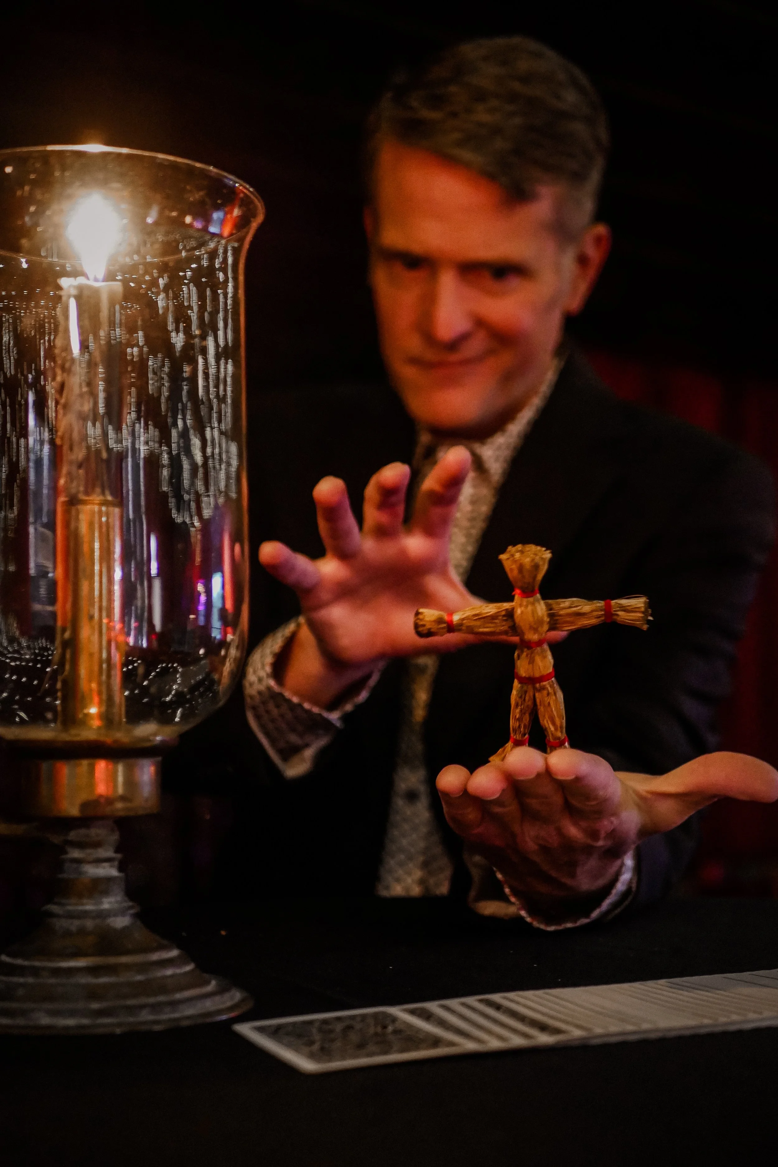 Rob Hoover holding a small straw figure beside a candle during a performance.