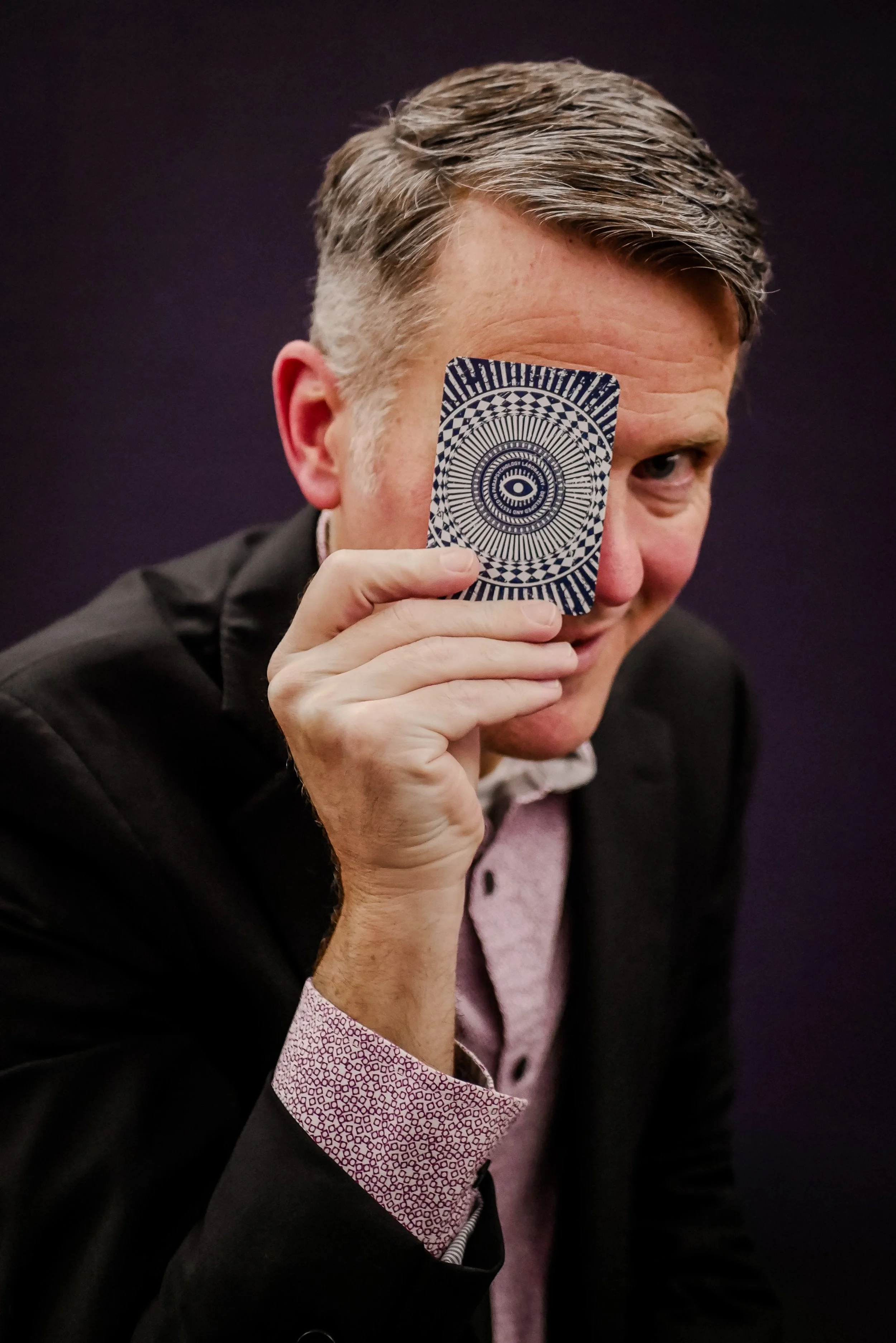 Rob Hoover holding a card with an illustrated eye in front of his face.