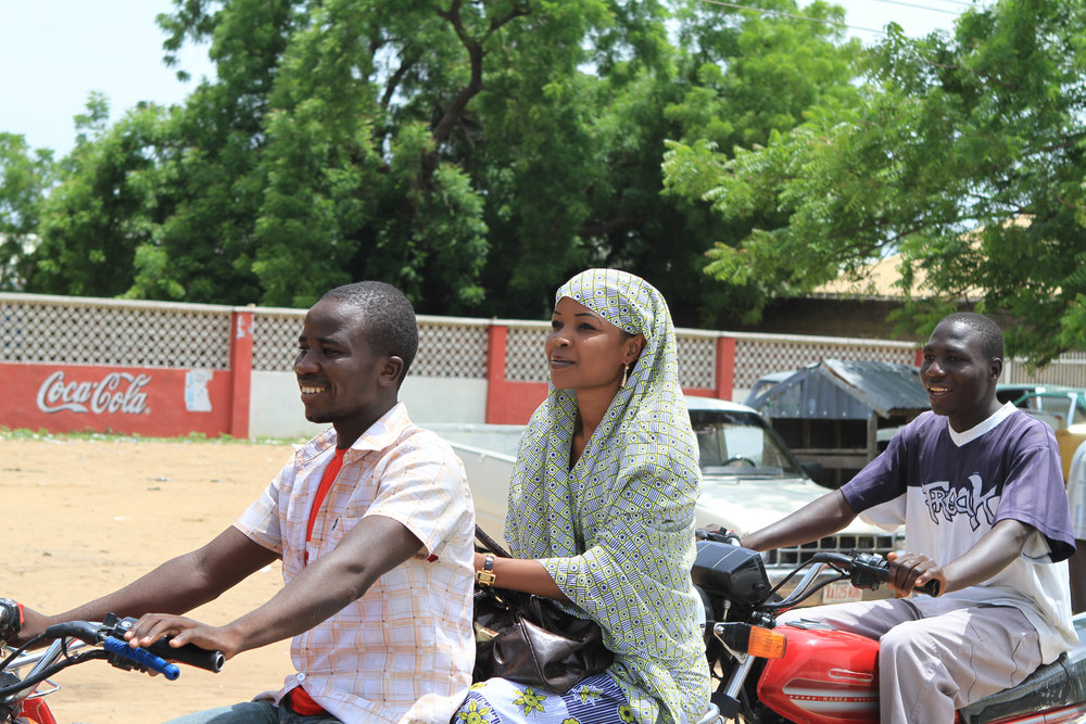  A couple ride a motorcycle beside the polio rally truck.&nbsp; 