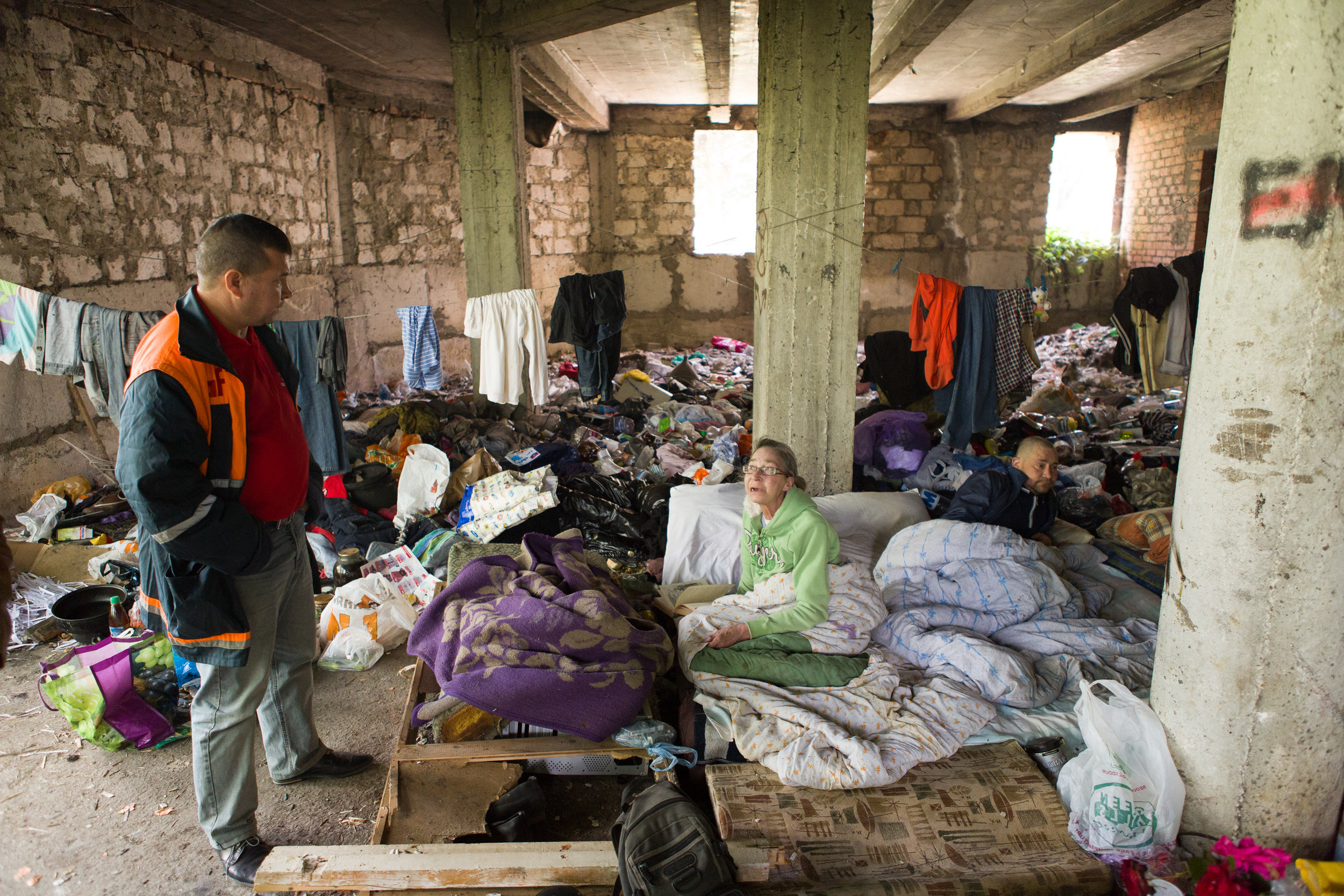 Katerina, 60, spends her days reading in this abandonded building site in Chisinau, Moldova where many people who are homeless gather to rest and sleep. The NGO Act for Involvement helped Katerina finish her treatment for tuberculosis earlier this year. An AFI doctor, Valeriu Coada, checks on Katerina and others who stay here. Valeriu and colleagues from the AFI mobile team regularly take people who are homeless for TB screening.