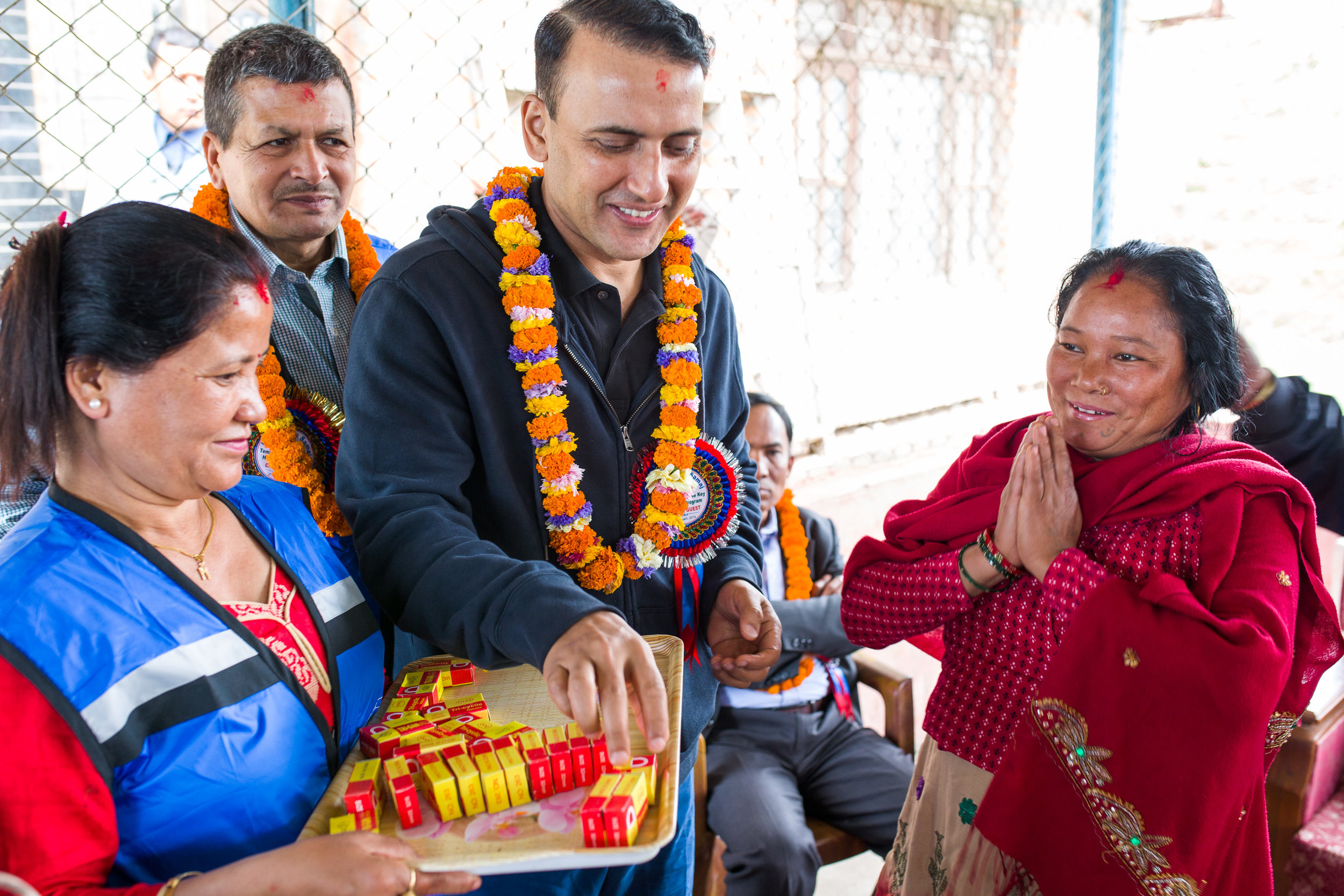 During a ceremony, Siddhi Aryal hands a symbolic key to one of the beneficiaries of the house-building project he and his wife Smriti helped to lead together with Nepali friends. Behind Siddhi is Pralhad KC, the Chairman of the Kavre Service Society (KSS) that oversaw construction of the homes.