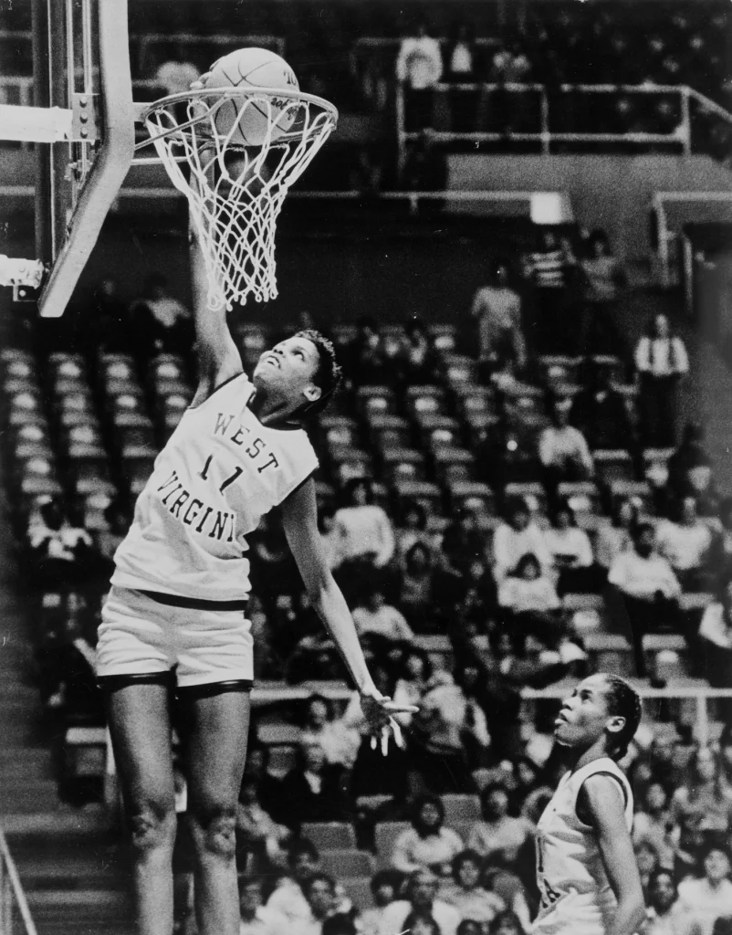 On December 21, 1984, 6 foot 7 inch West Virginia junior Wells became the first woman to dunk a basketball in competition. It would be a full decade before another woman would do the same and 25 years before video proof of Wells' dunk was unearthed and made public. Following her college basketball years, Wells played professionally in Europe and toured with the Harlem Globetrotters. 