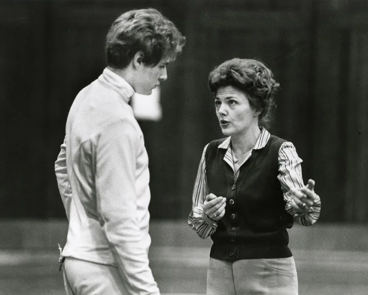 Charlotte Remenyik was born on Sept. 5, 1934, in Hungary, an only child to parents of the upper middle class of that country. She learned to fence at a young age. In an interview conducted by OSU Quest in 1981 she said: “I love sabre fencing the best…Although they don’t allow women to compete in sabre or epée, only foil, that is what I grew up with in Hungary—in Transylvania. My cousins, all boys, would come home from military school on vacation, and they would practice their sabre fencing. I was the youngest cousin and the only girl, and they would say, ‘No, Charlotte, you cannot do that. You are a girl, and you are too small.’ I guess that irked me enough to go out and learn sabre.” In 1978 Charlotte Remenyik came to Ohio State to coach the OSU women. In the fall of 1980 she made OSU history by becoming the first woman to coach a men’s varsity team—and as the first woman to coach both the men and the women concurrently.