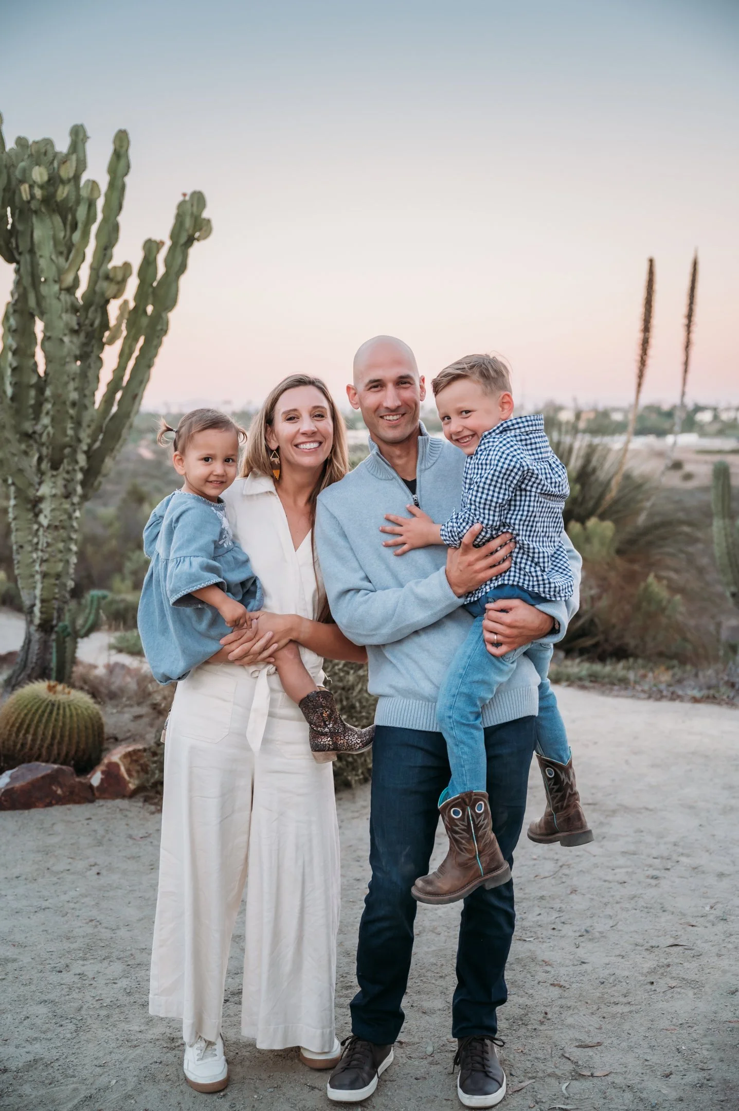 Family of four outdoors in a desert setting, smiling, with cacti in the background Alisha Mowry Photography Military, Brand, and Portrait Photographer San Diego CA