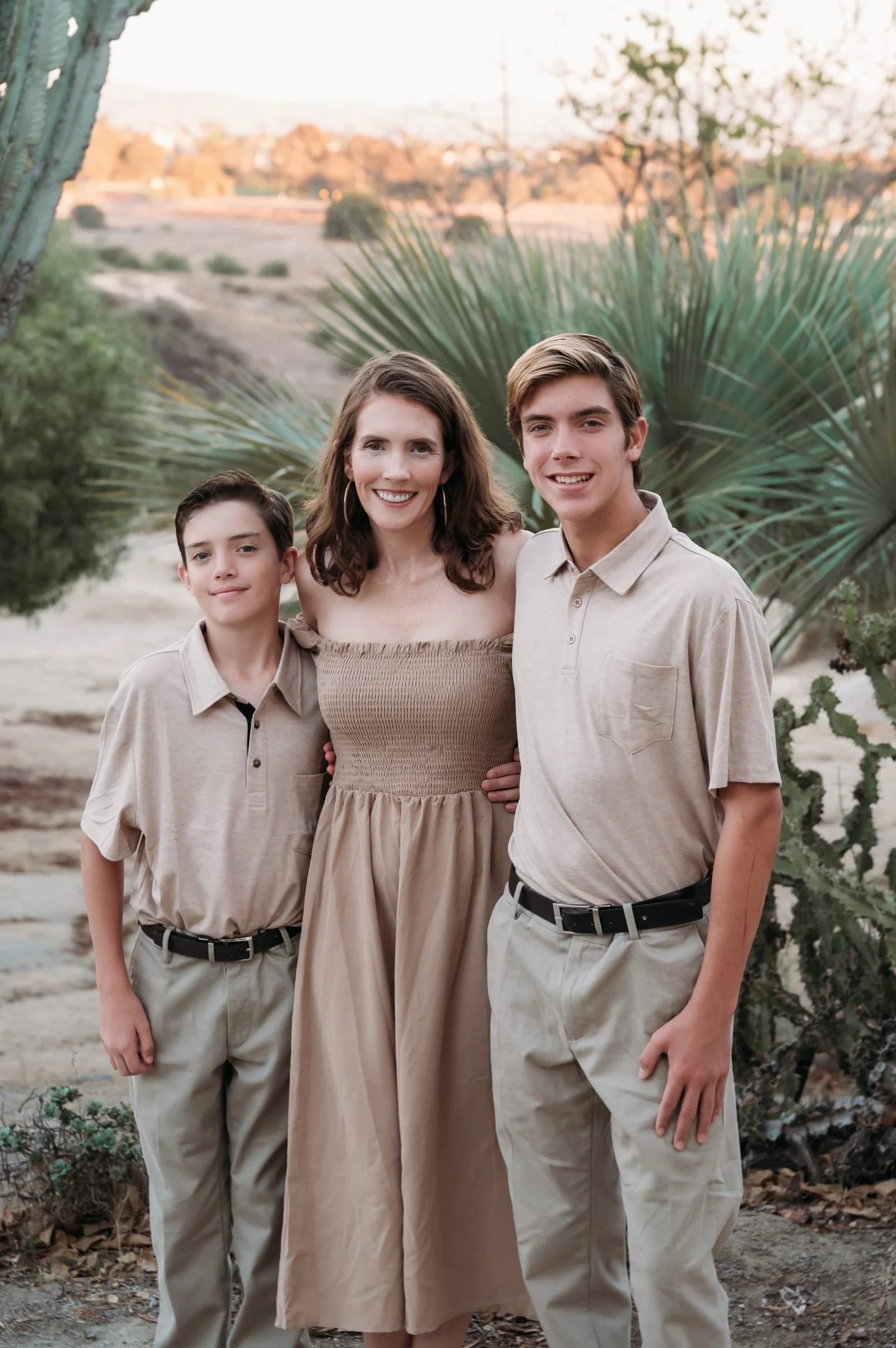 A woman with two boys outdoors during sunset, surrounded by desert plants and cacti. Alisha Mowry Photography Military, Brand, and Portrait Photographer San Diego CA