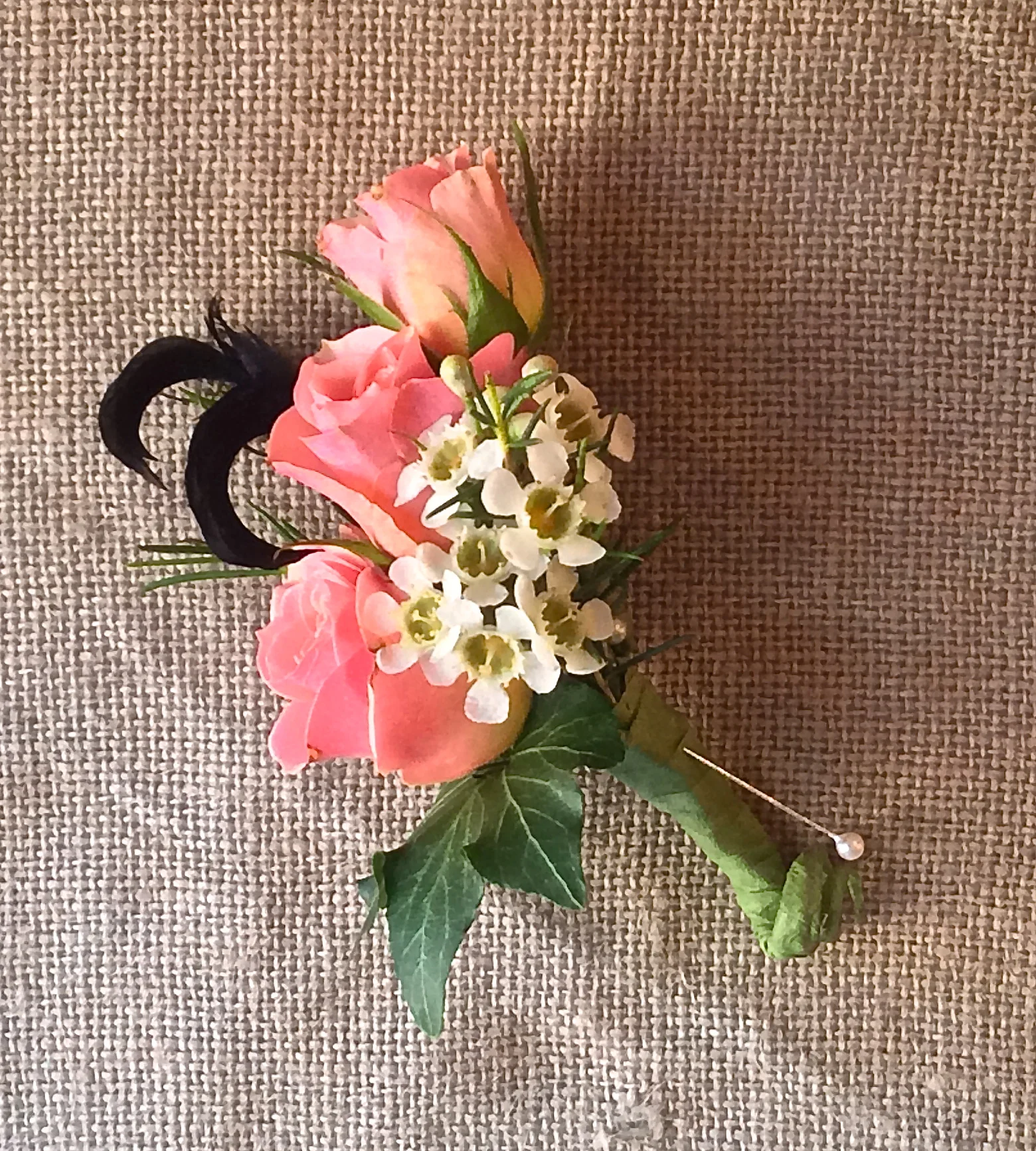 Spray roses, waxflower, ivy and feathers.