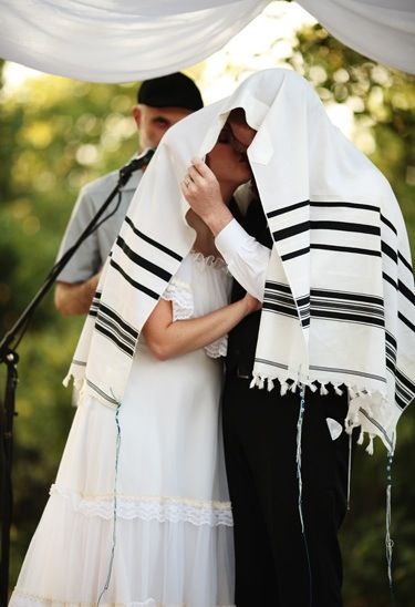 At a traditional Jewish wedding ceremony, the bride and groom will share their first kiss under a prayer shawl. 