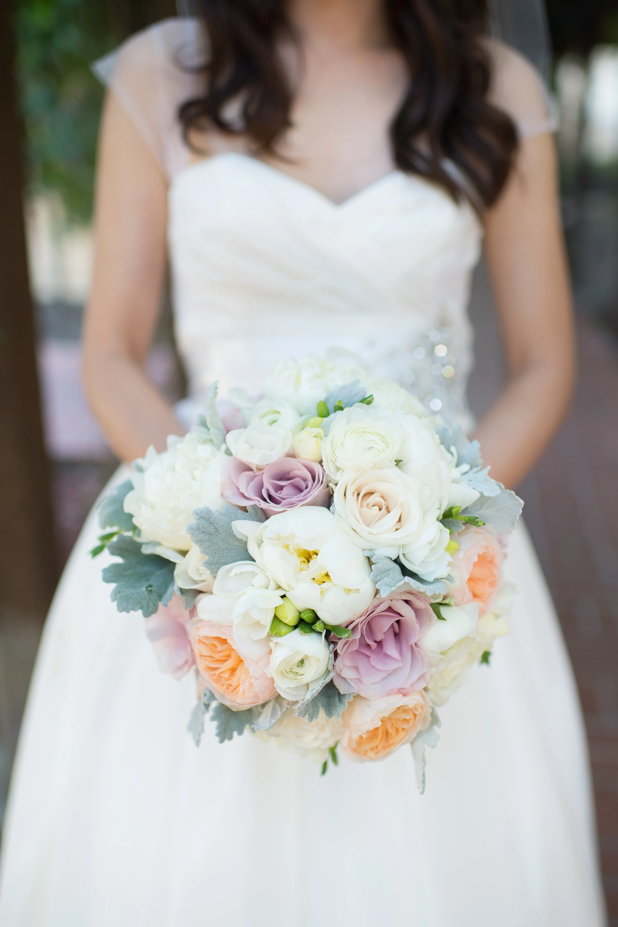 Peachers carried a bouquet of peach, blush and ivory flowers: white peonies, peach garden rose " juliet" , white freesia, and white ranunculus with dusty miller.