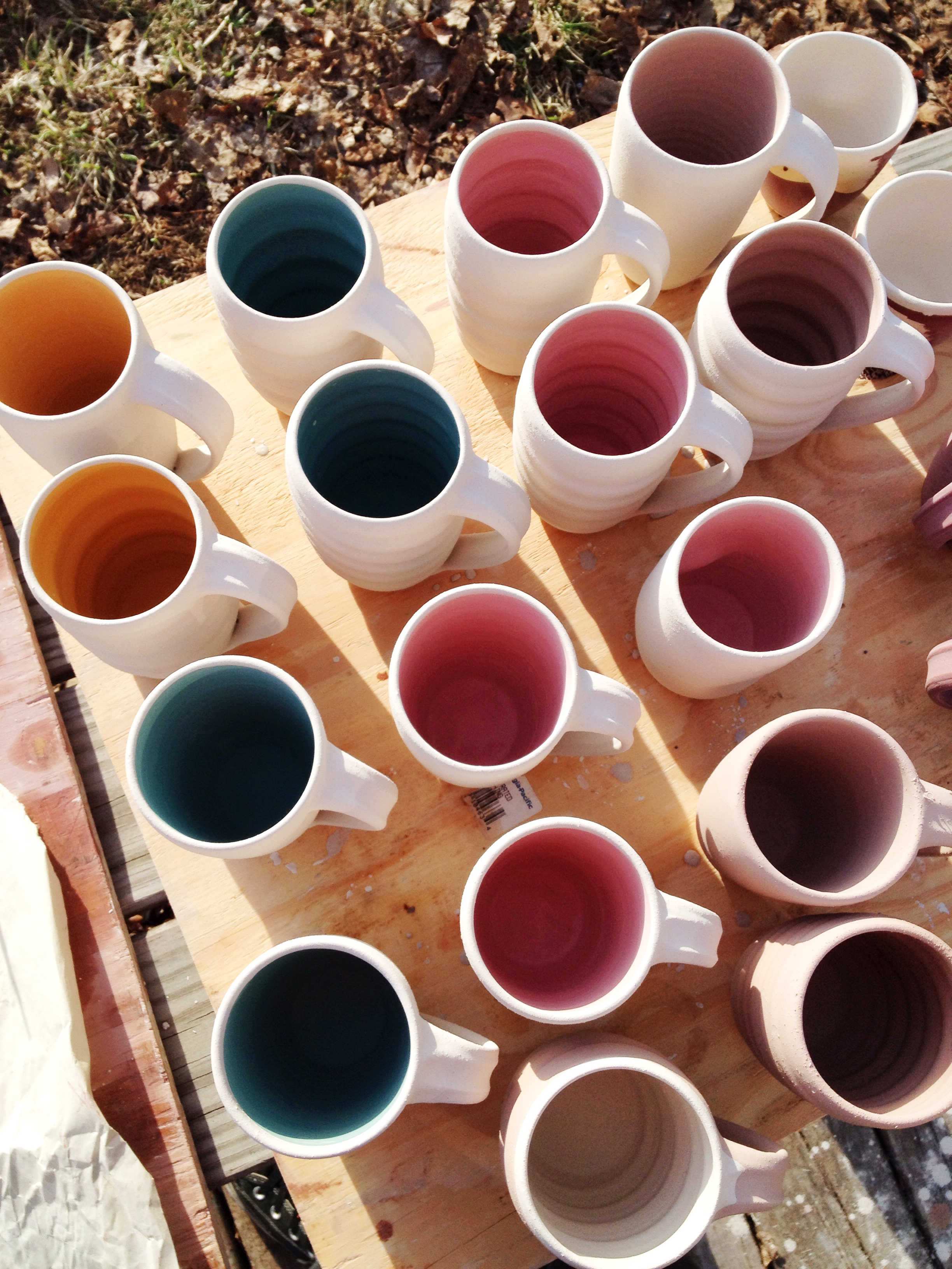 An assortment of the new smooth-sided mugs and the classic ripple mugs, glazed with bright pops of color on the interior and a soft cream on the exterior. 