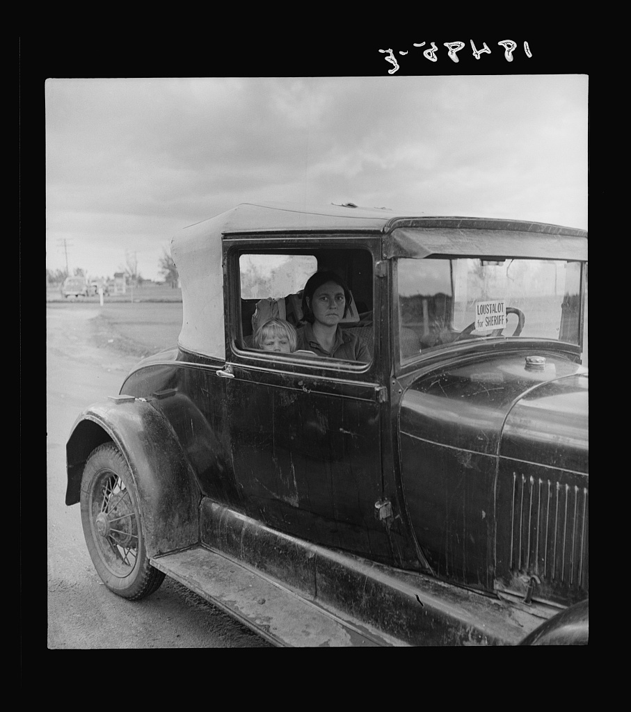  During the cotton strike, the father, a striking picker, has left his wife and child in the car while he applies to the Farm Security Administration for an emergency food grant. Shafter, California. 