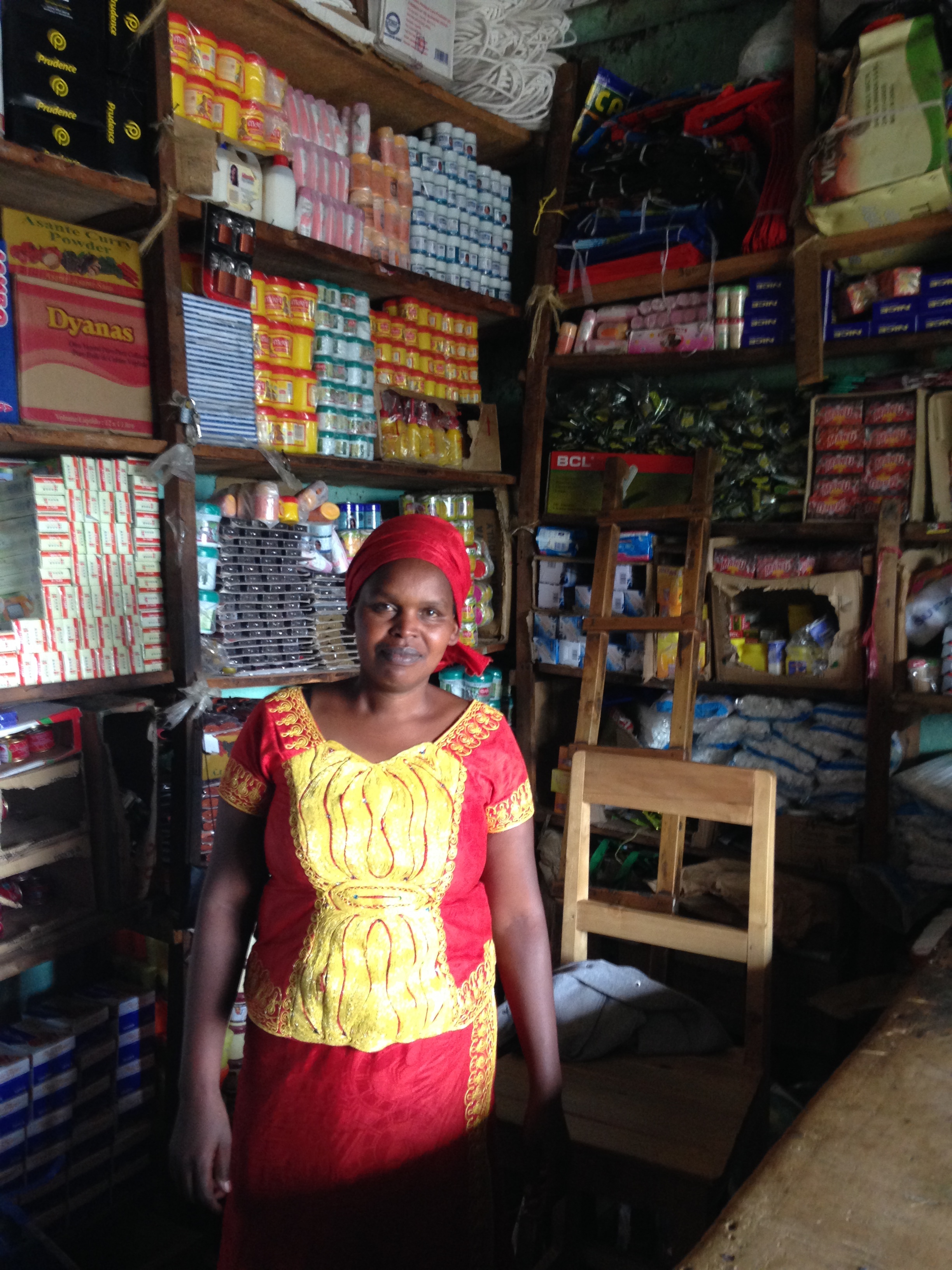 A microentrepreneur in Rwanda stands in front of her store.