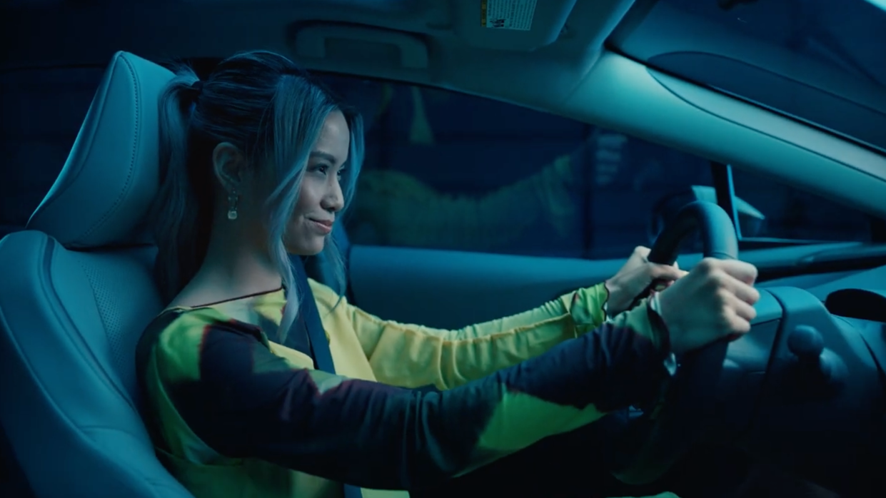 Woman with multi-colored hair sitting in car, driving at night
