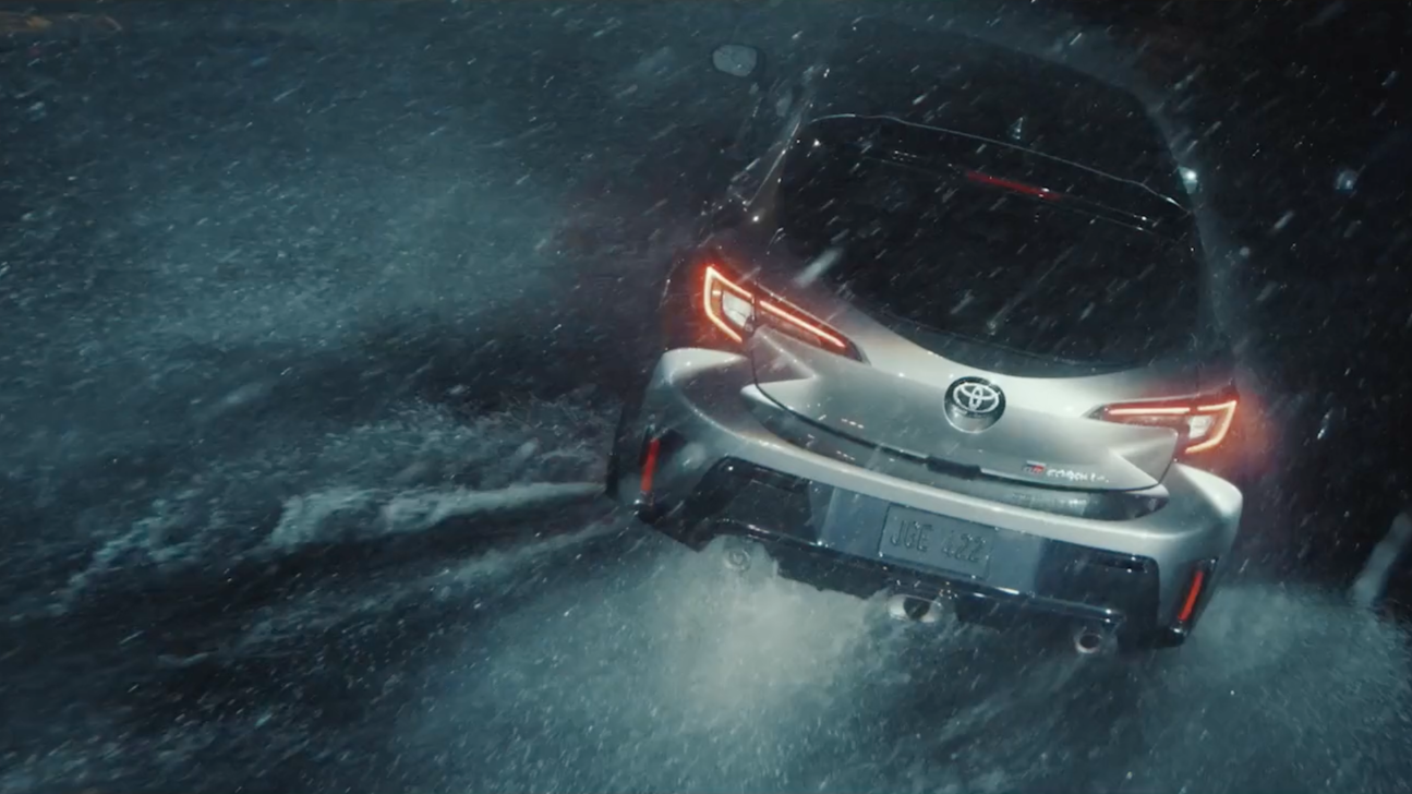 A silver Toyota sports car driving through heavy rain at night.