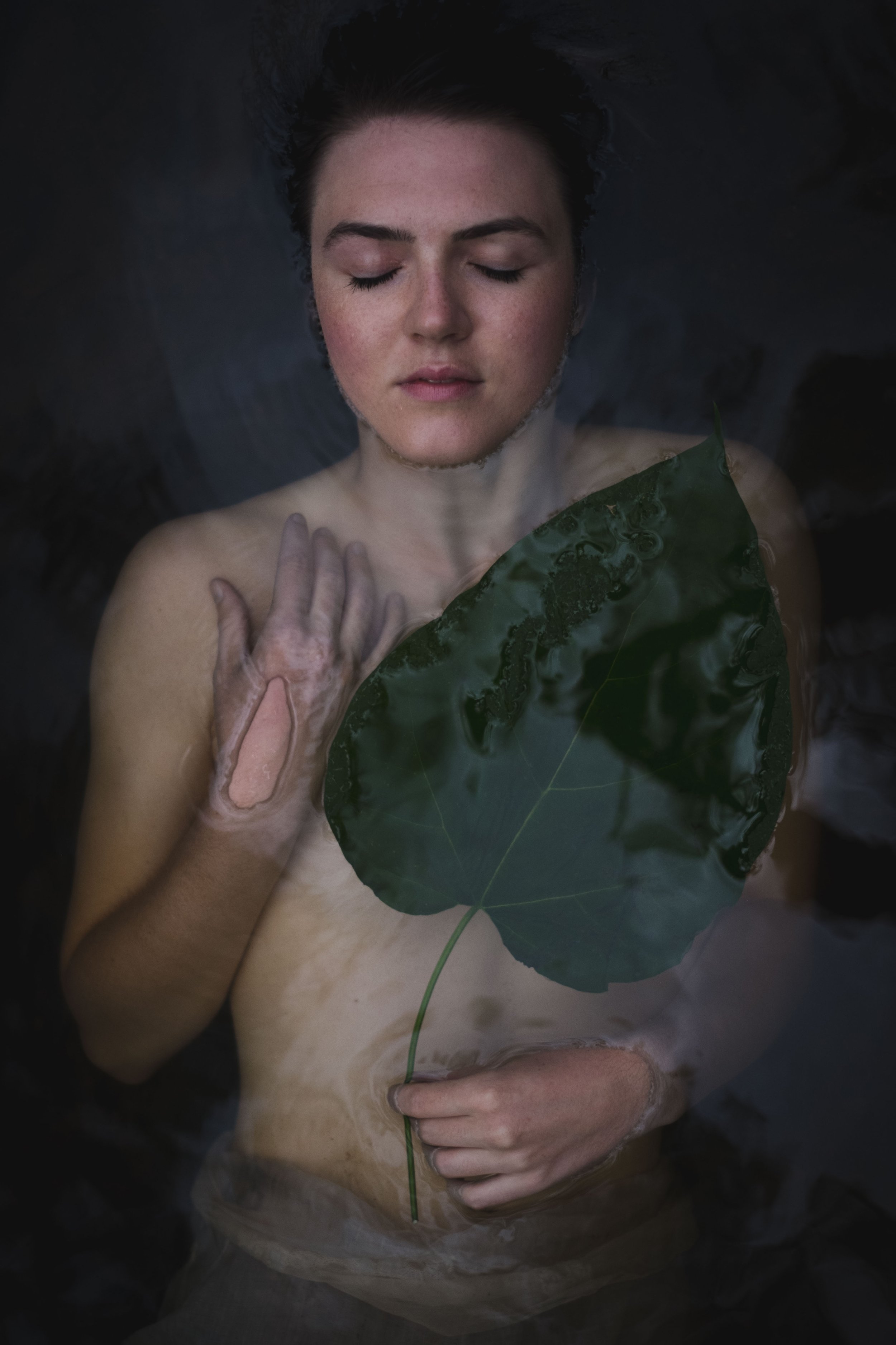 woman holding a green leaf peacefully floating in water