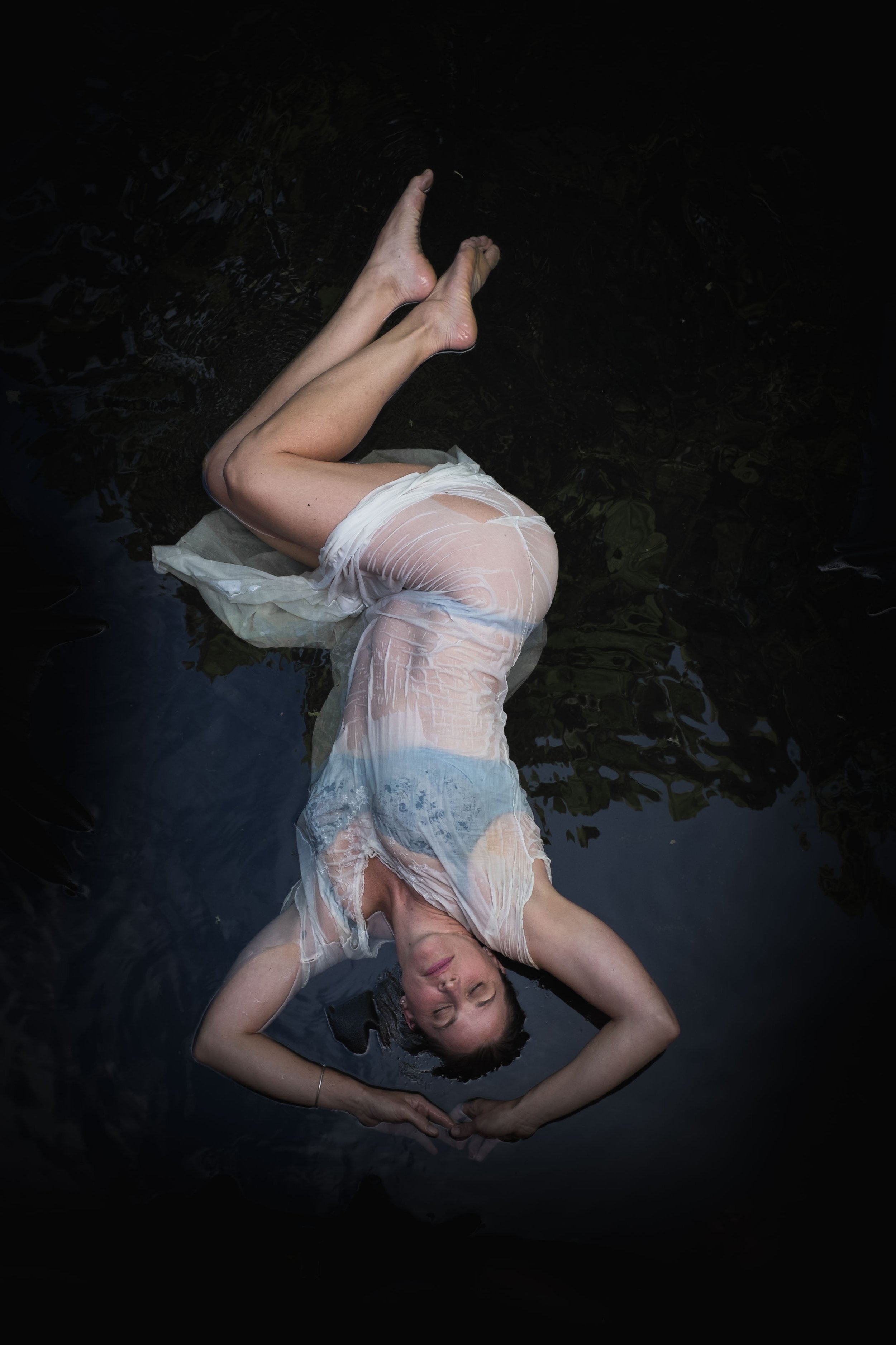 top down shot of woman floating in water wearing a sheer antique dress